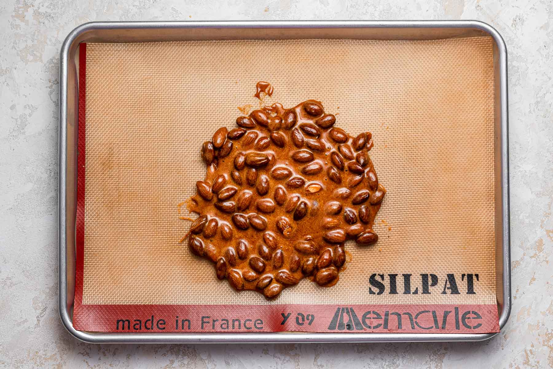 Almond brittle poured on silicone baking sheet.