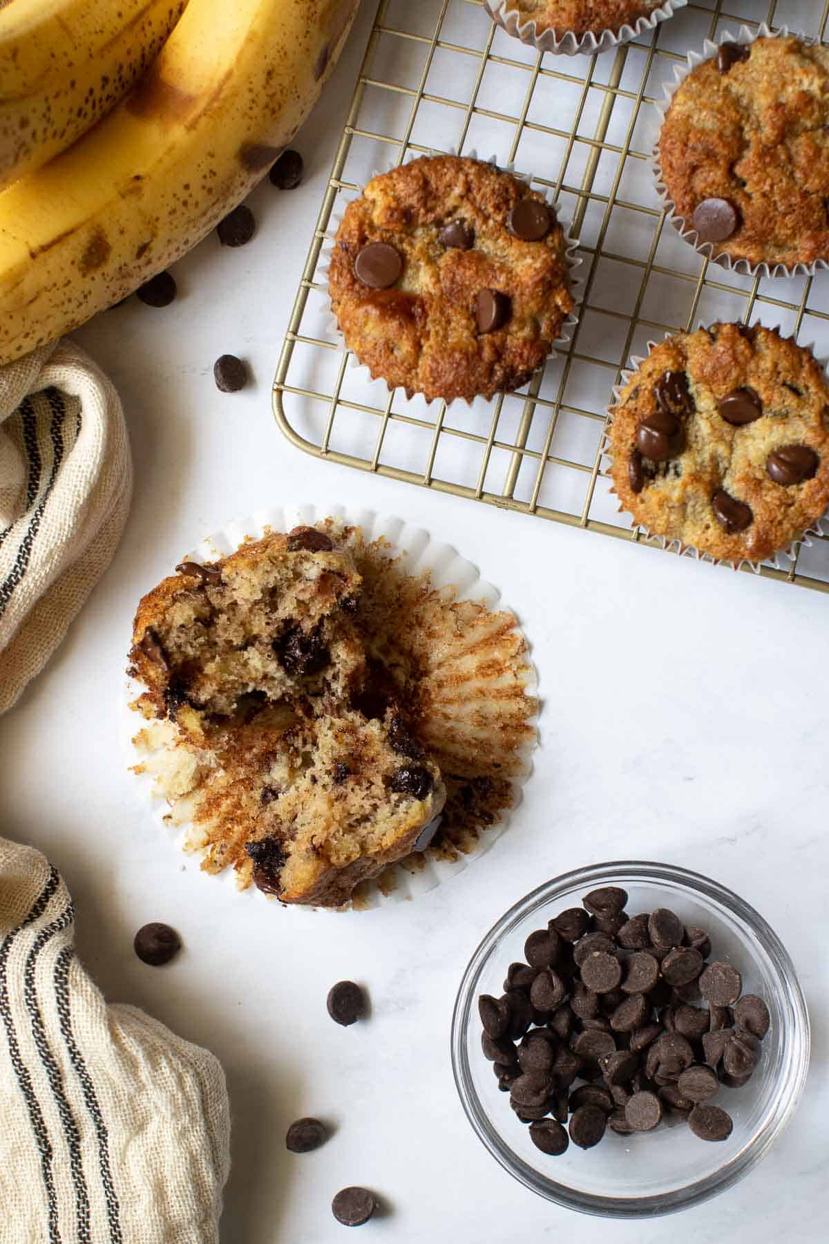 Banana muffin split open with bowl of chocolate chips on the side.