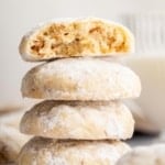 Stack of almond snowball cookies with top one cut in half.