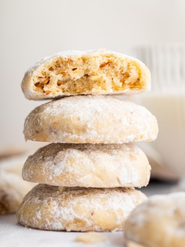 Stack of almond snowball cookies with top one cut in half.