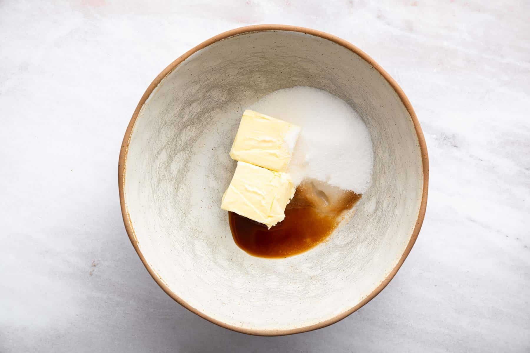 Pretty porcelain bowl with chopped butter, sugar and vanilla.