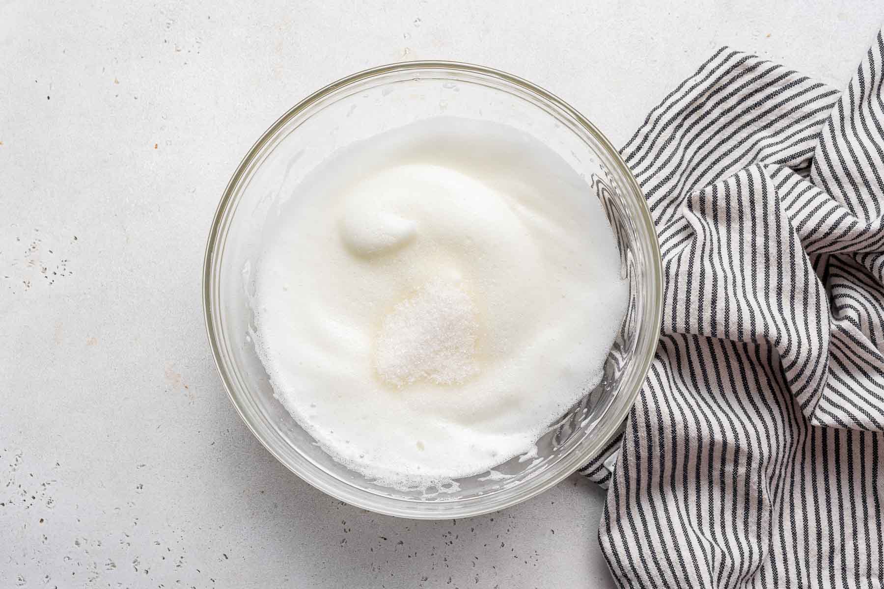 Adding sugar to beaten egg whites.