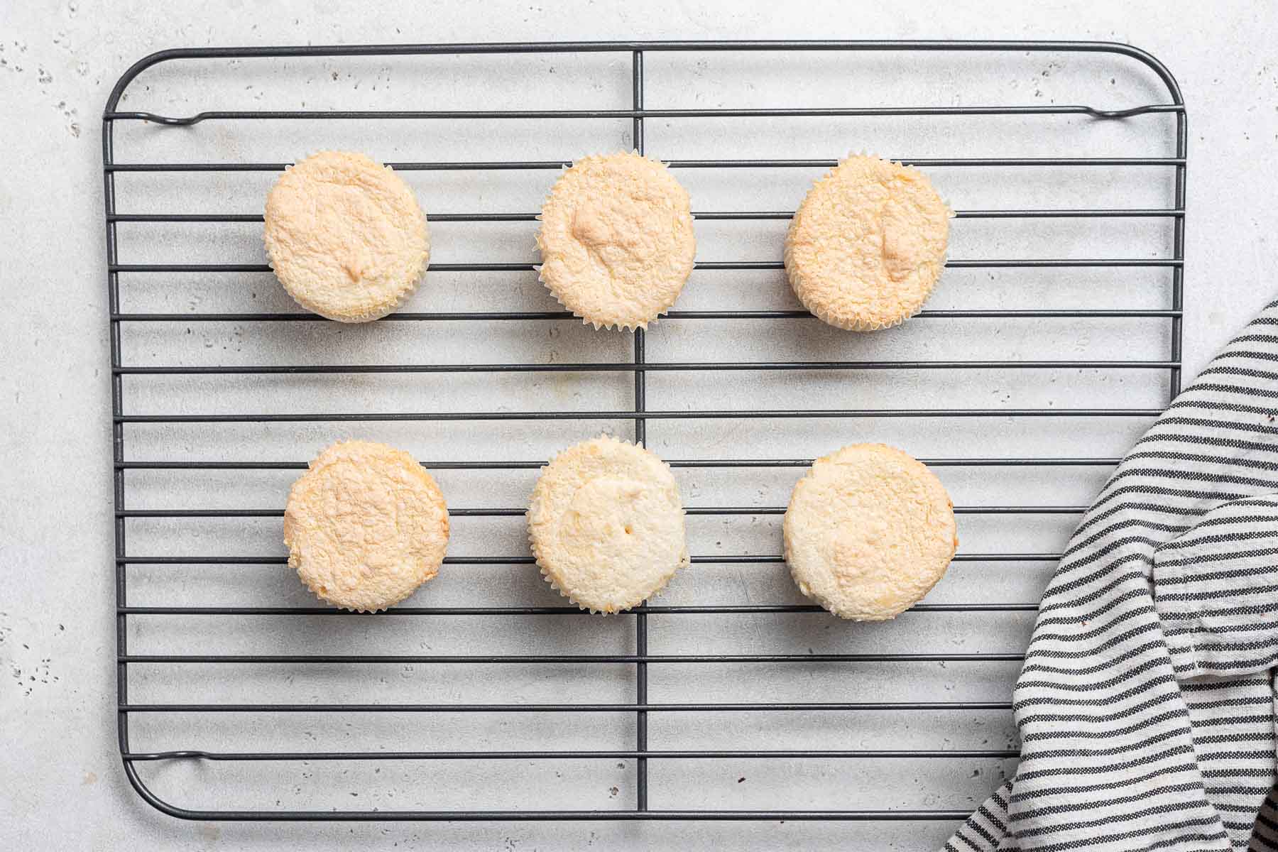 Baked angel food cupcakes on a wire rack.