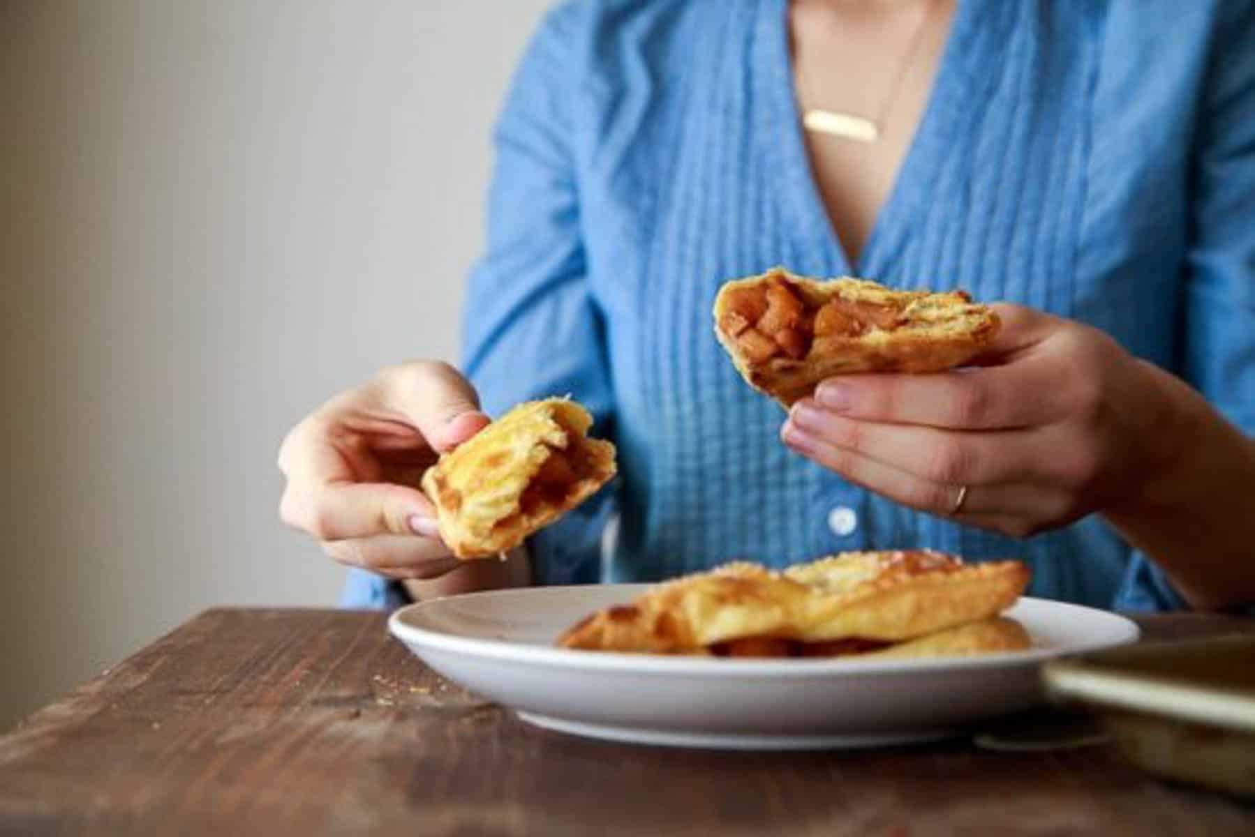 Woman in denim holding apple turnovers split open.