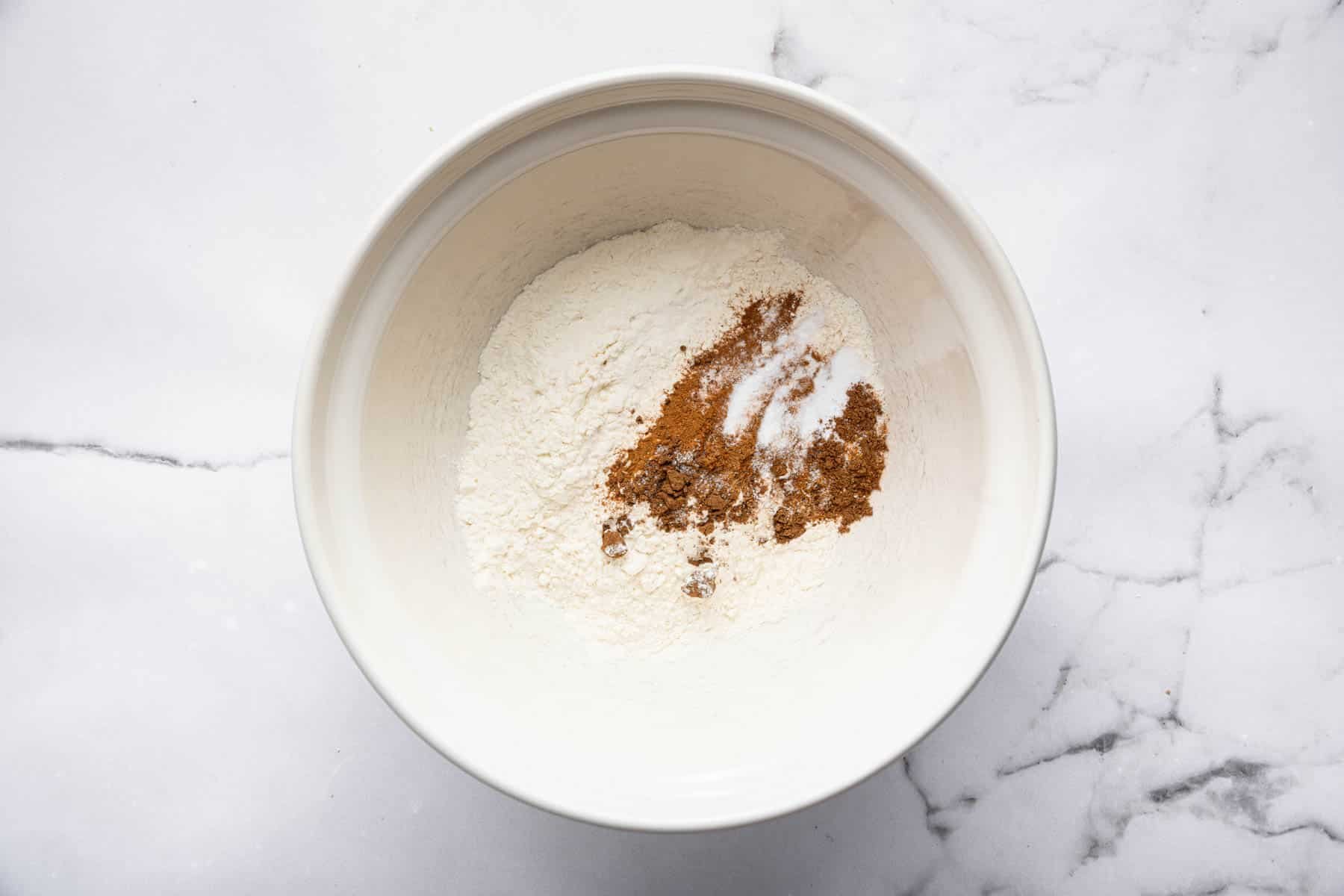 White bowl with flour and spices sprinkled on top.