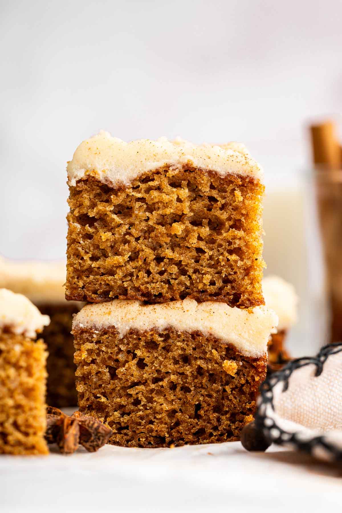 Two square brown slices of applesauce cake with tan frosting stacked.