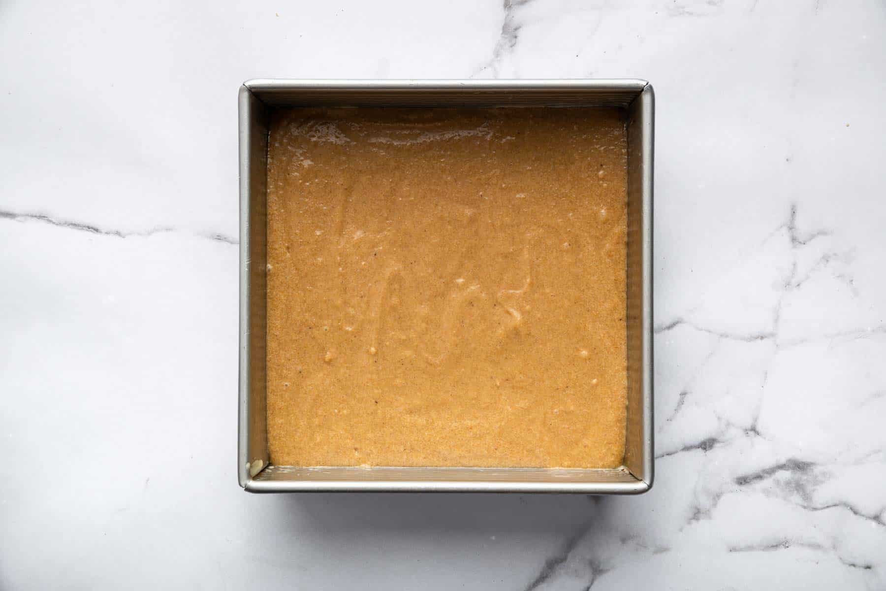 Raw dessert batter in an 8-inch square pan.
