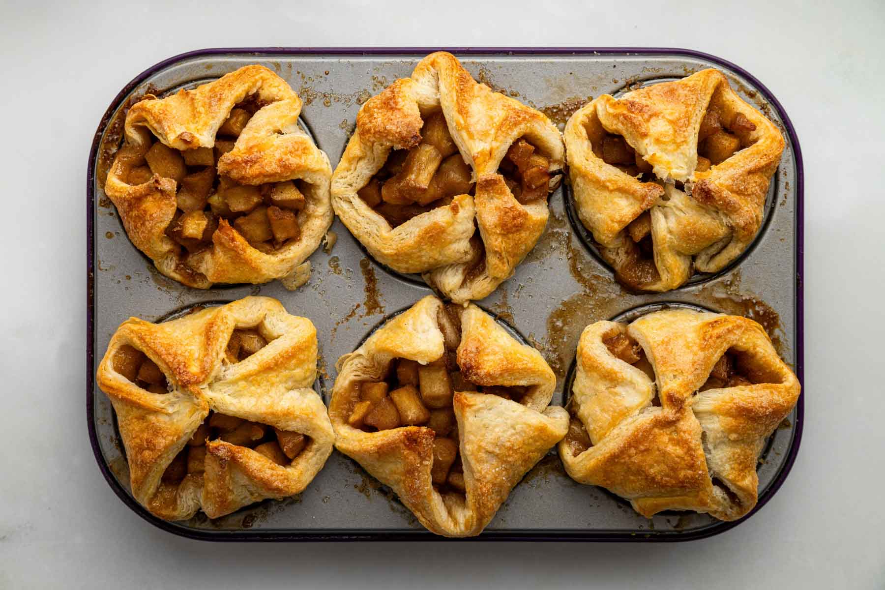 Muffin pan with freshly baked apple croissants.