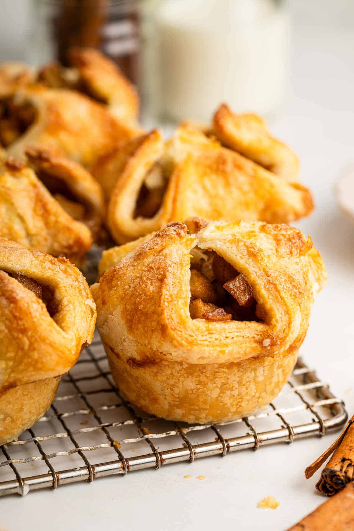 Apple puff pastry dessert in a muffin cup on a wire rack.