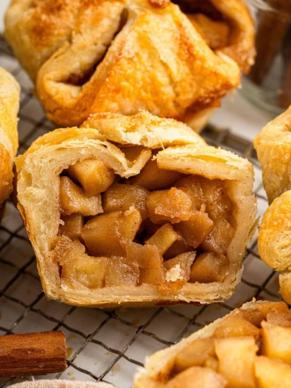 A baked apple croissant cut in half to show diced apples.