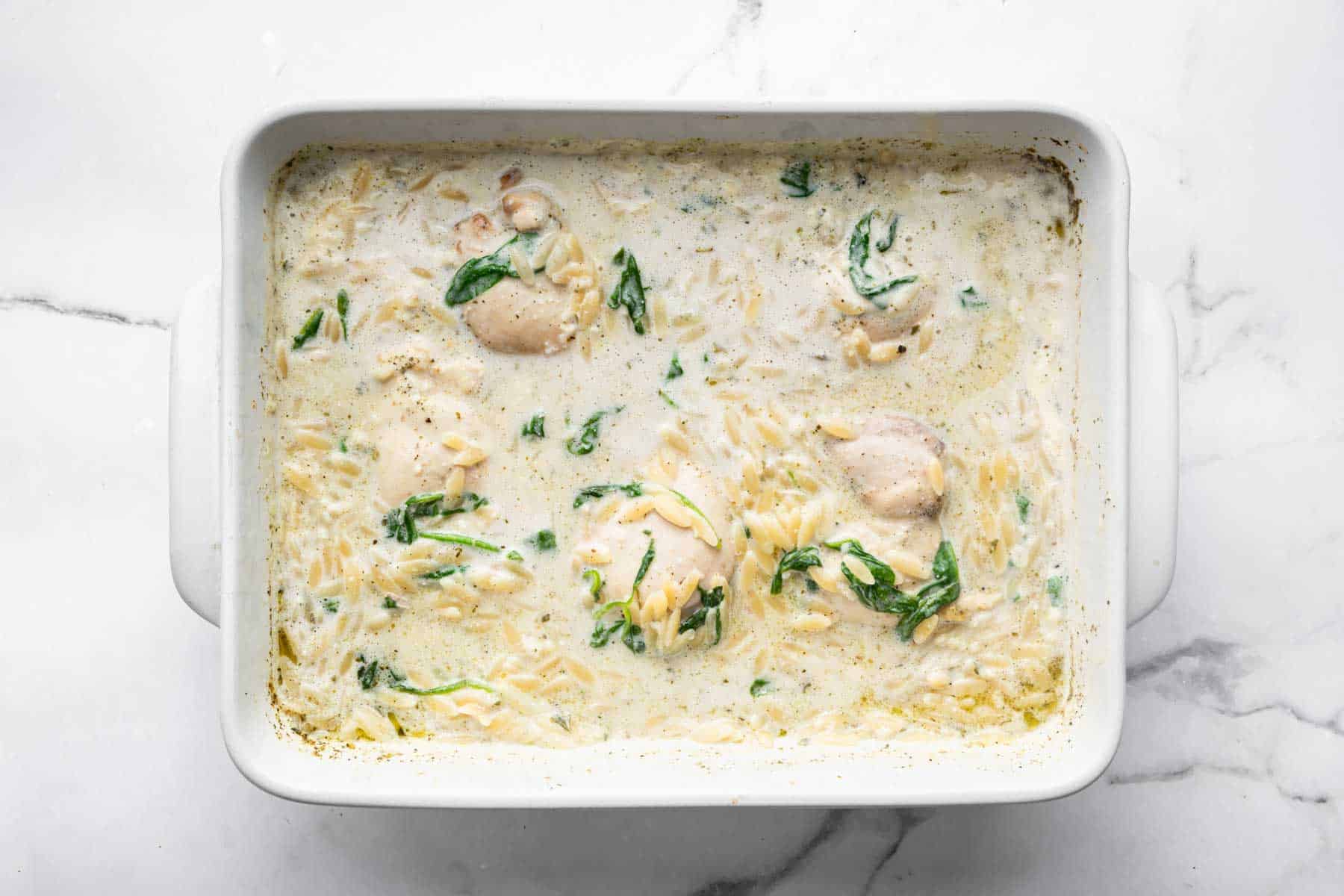 White rectangular baking dish with cream sauce and pasta.