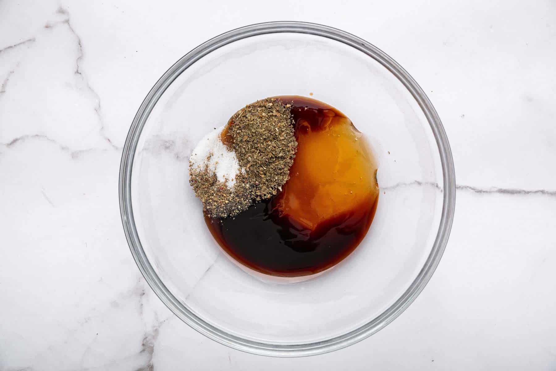 Glass bowl with brown liquid, tan liquid, and spices in it.