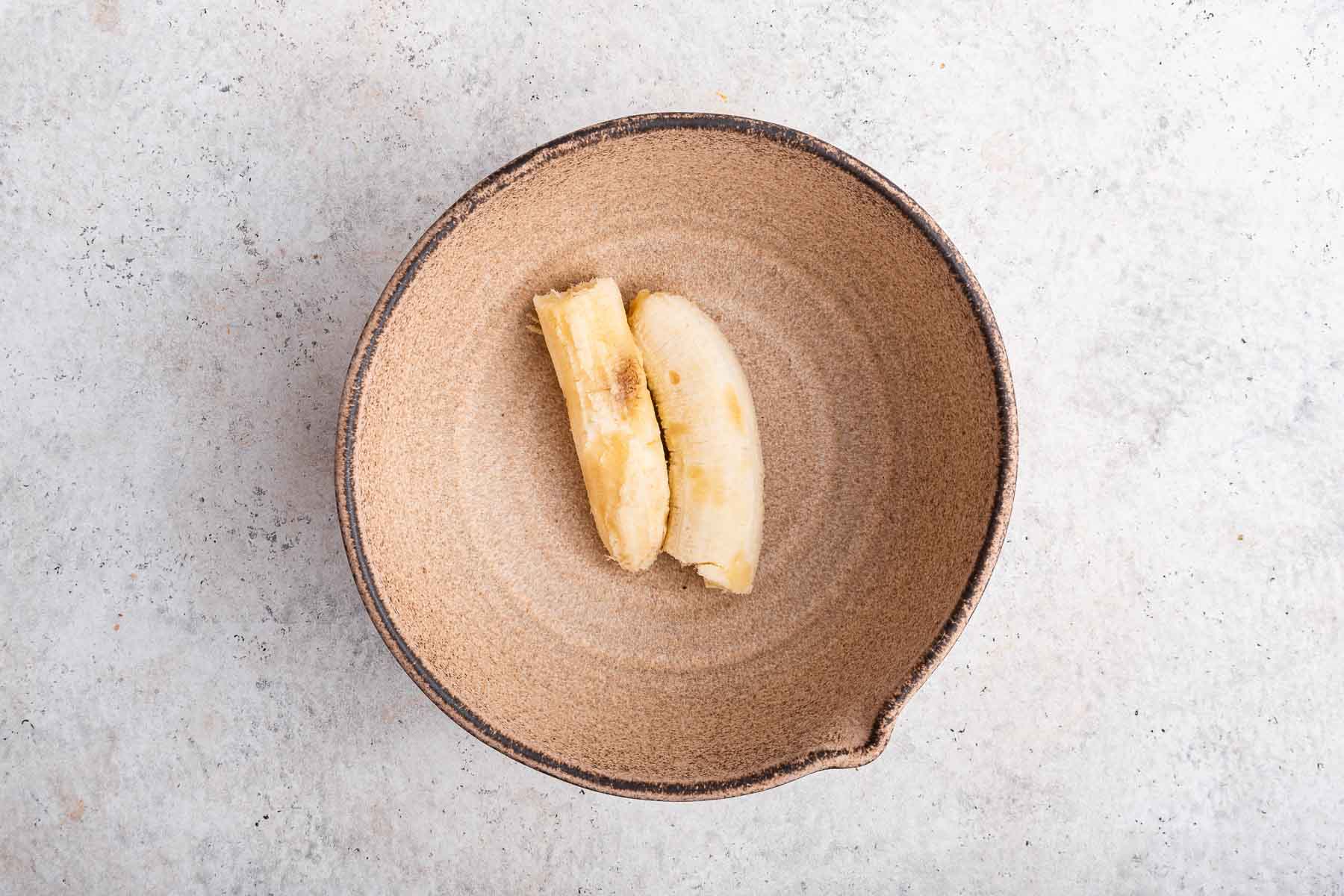 One overly ripe, soft banana in a brown bowl.