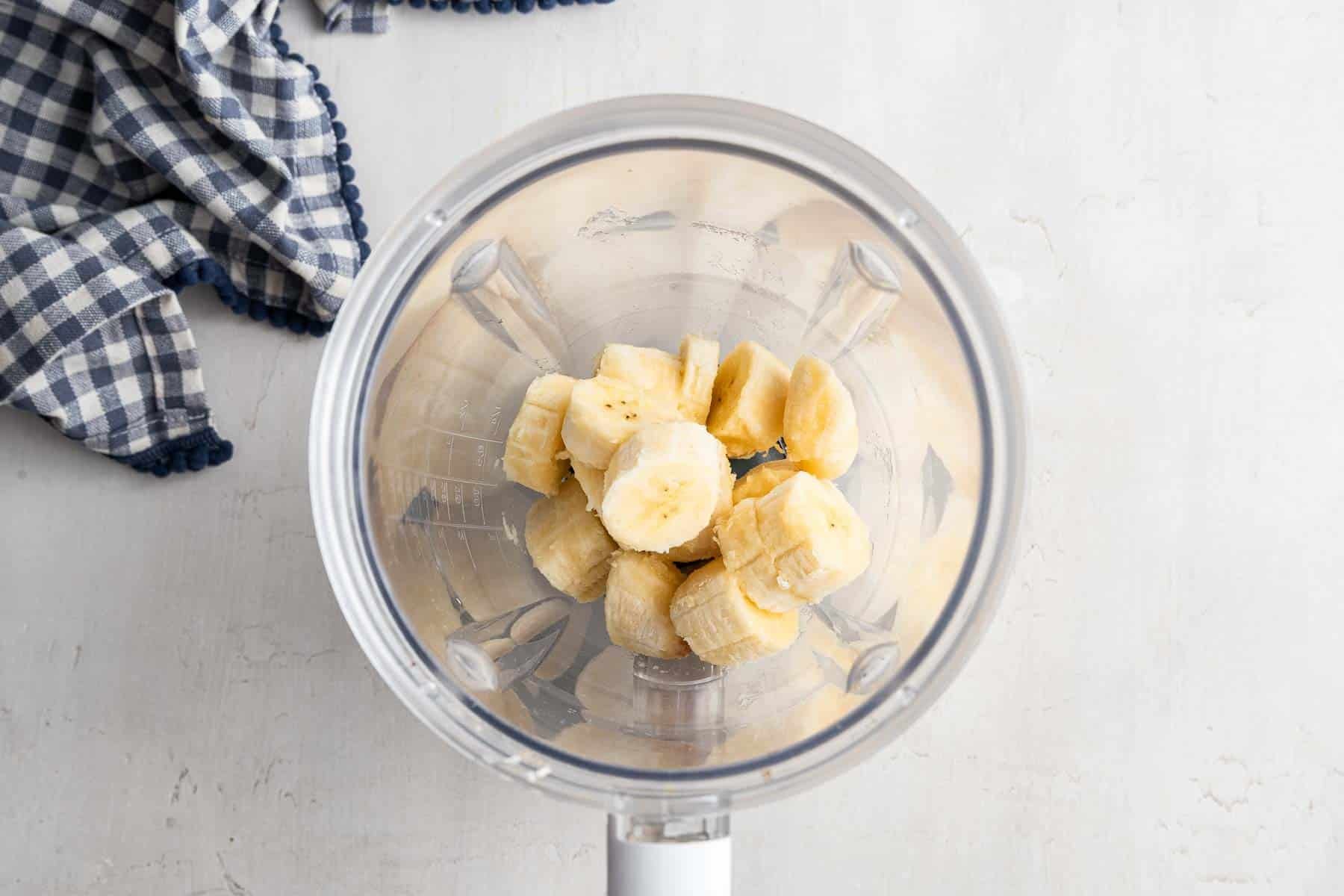 Blender with sliced banana in the bottom.