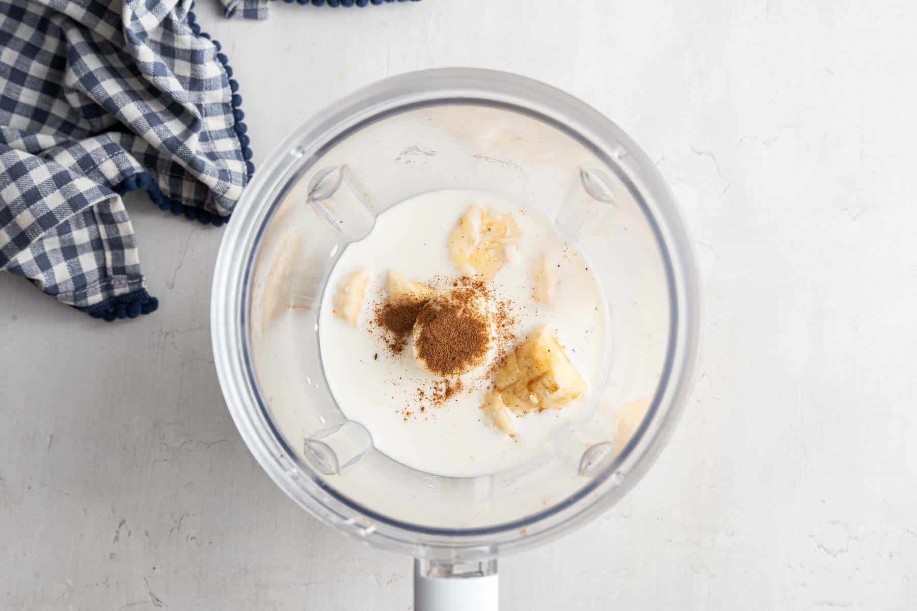 Blender with milk, cinnamon and lemon juice in the bottom.