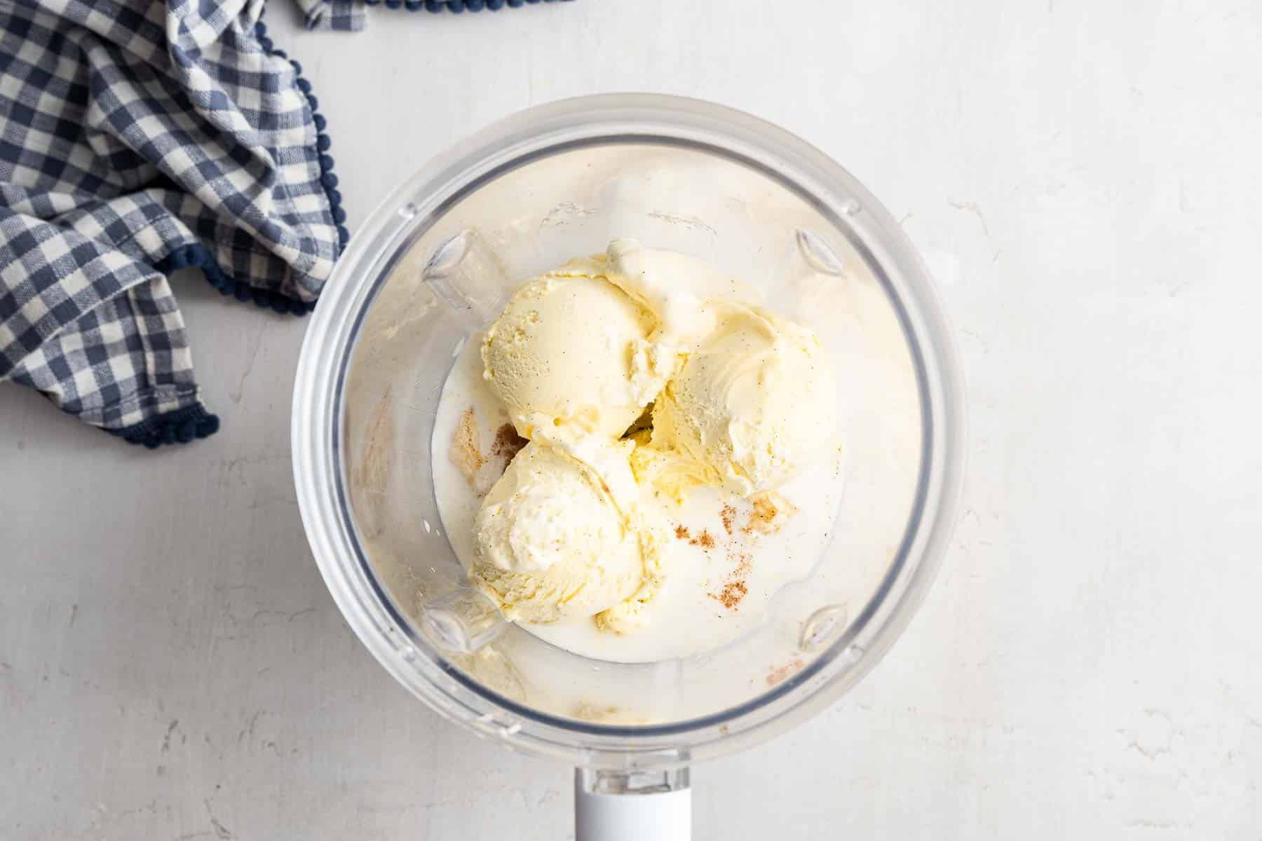 Three giant scoops of white ice cream in the bottom of a blender.