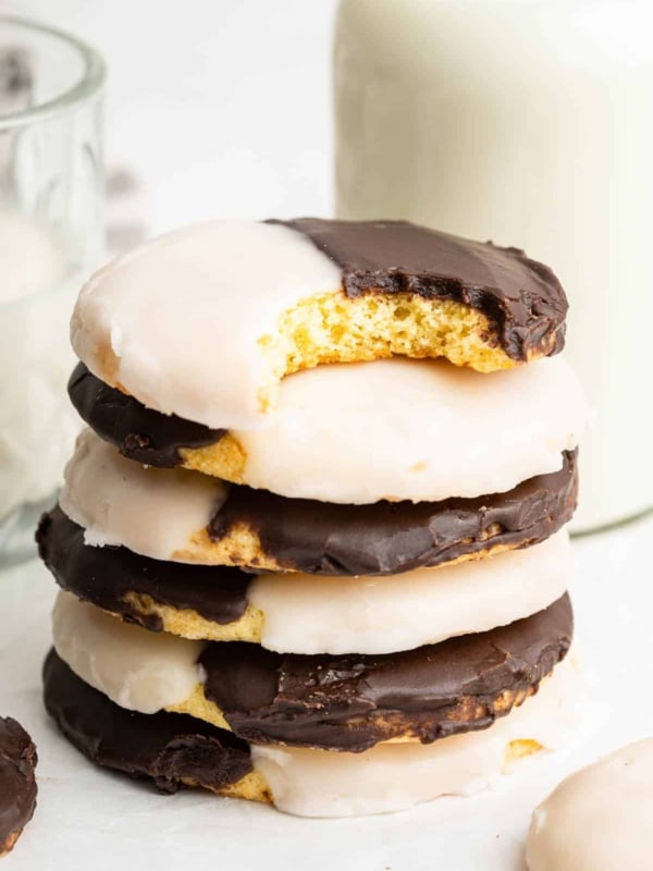 Stack of black and white cookies with one bite missing on top cookie.