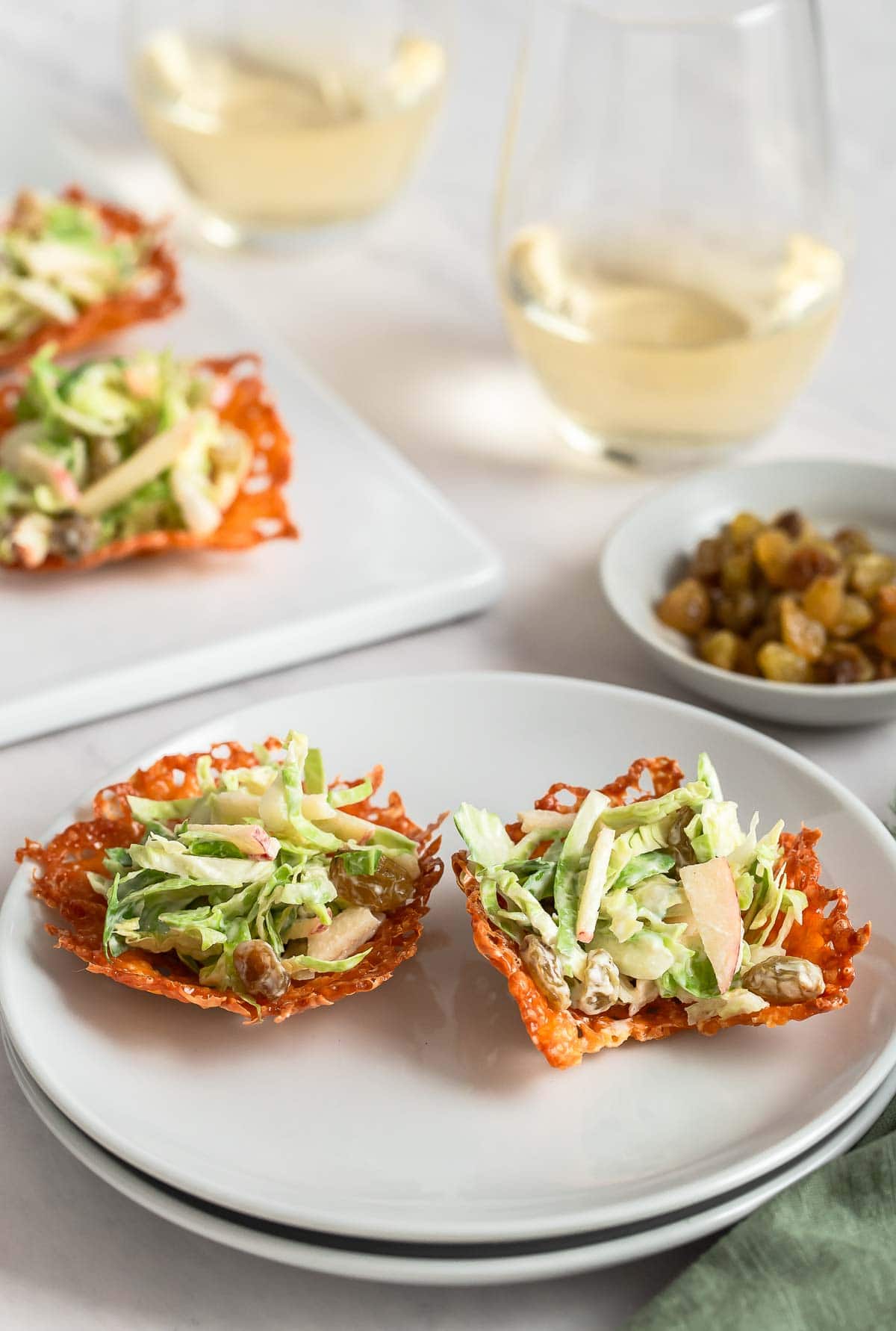 Brussels sprout slaw in cheese cup with wine glasses alongside.