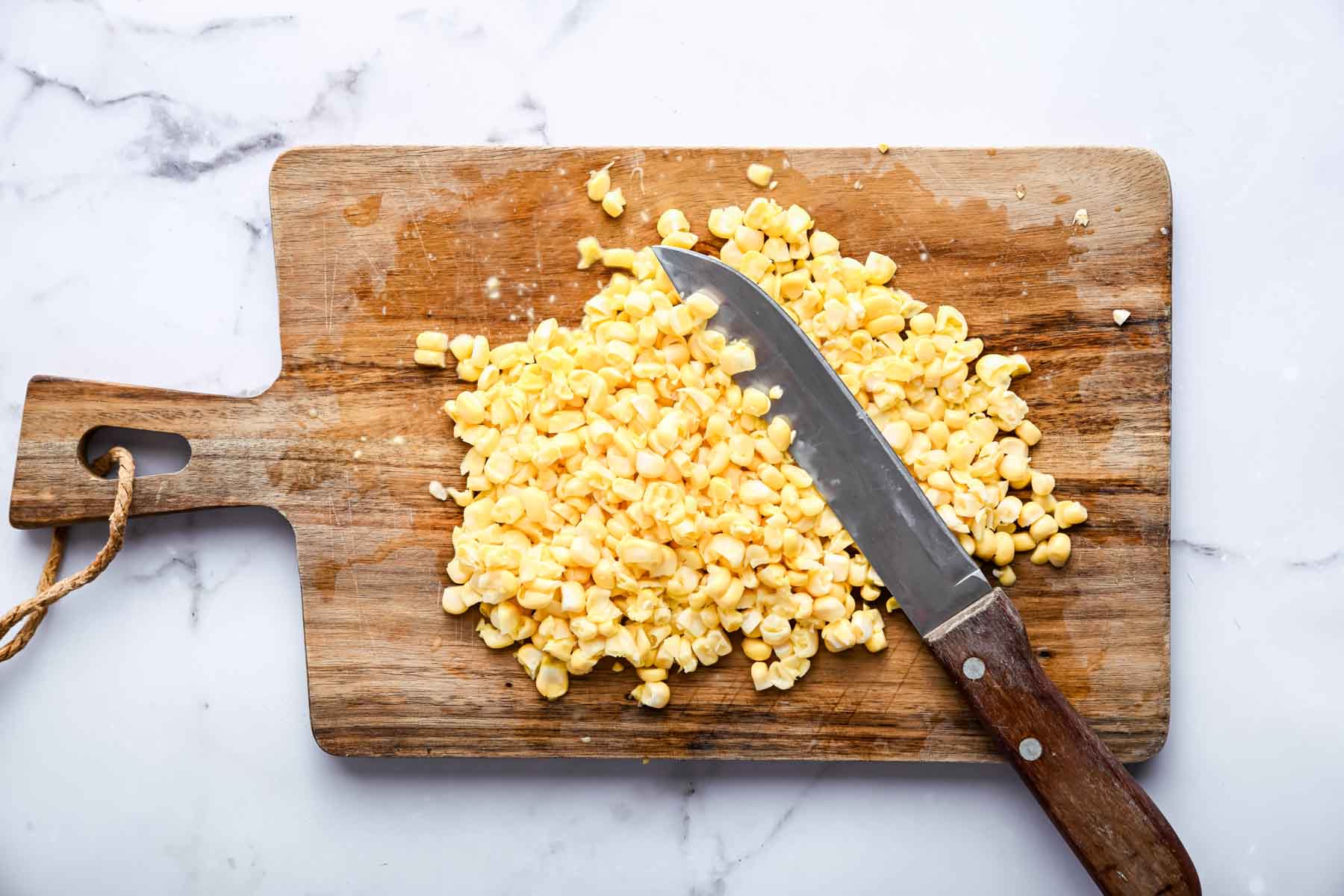 Chopped veggies on a wooden cutting board with knife on side.