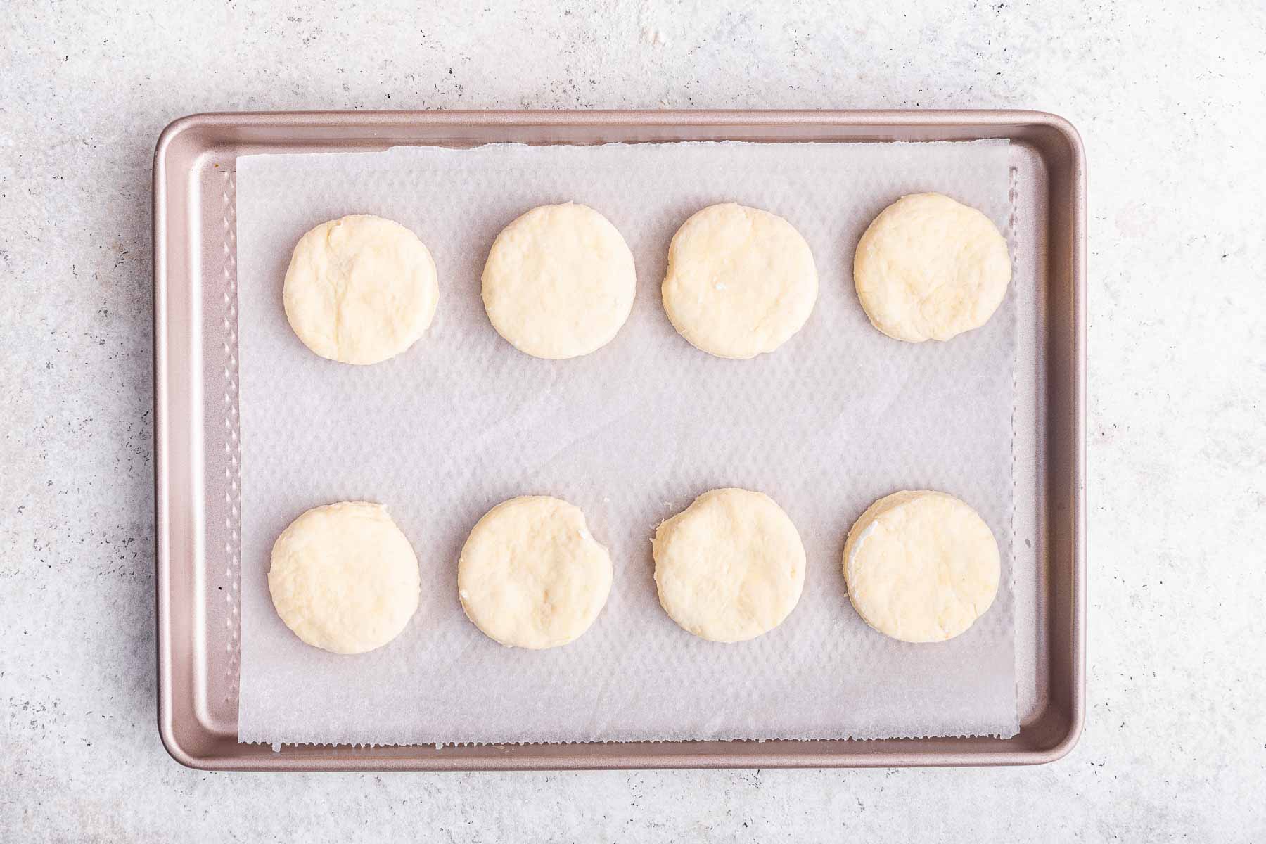 Eight homemade buttermilk biscuits on cookie sheet, before baking.
