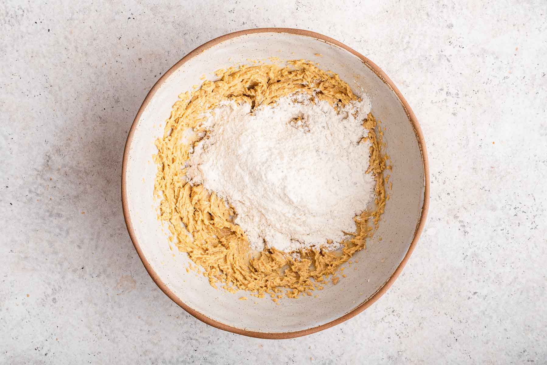 Dry ingredients poured on wet ingredients in cookie dough.