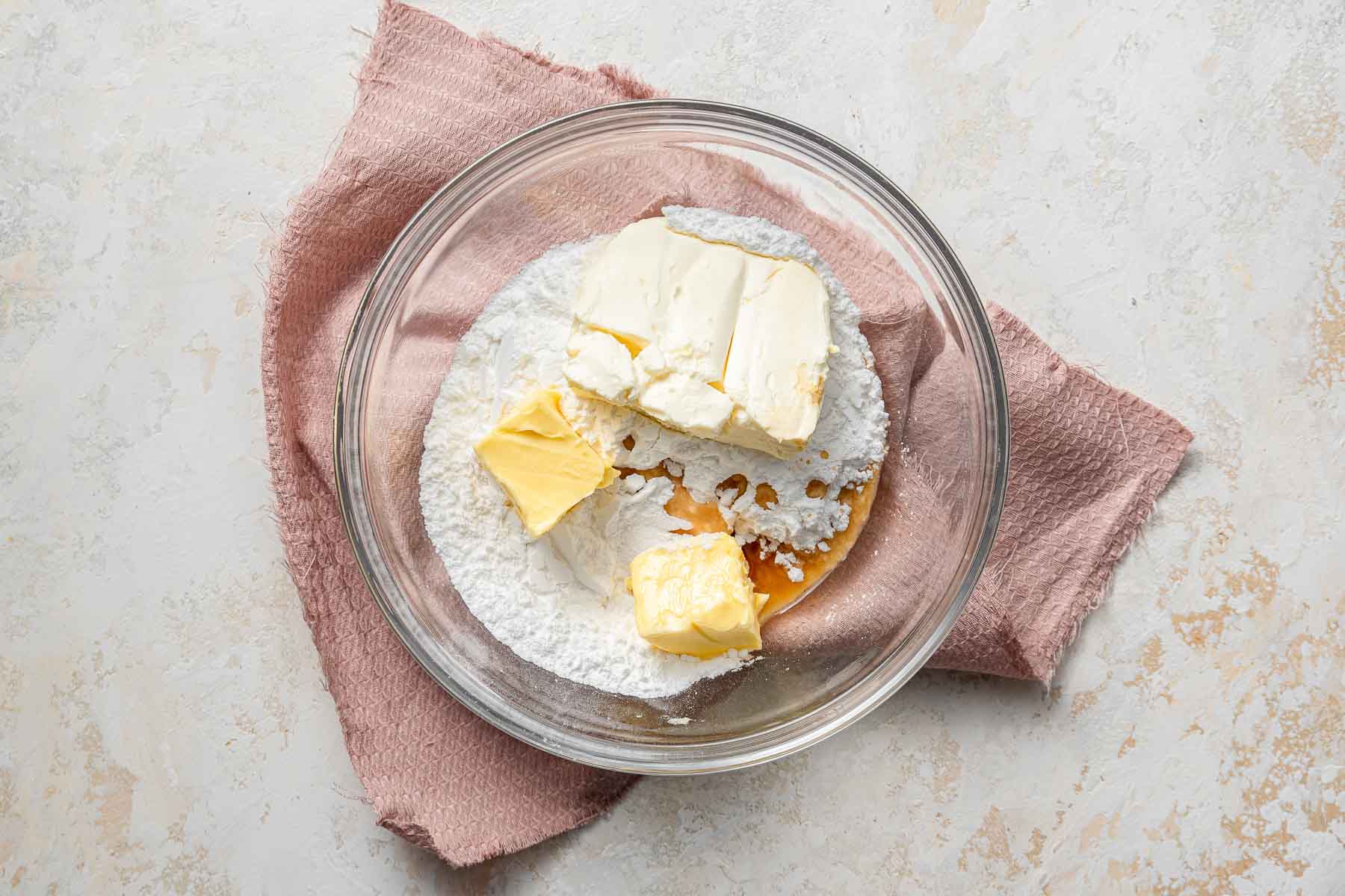 Ingredients for cream cheese frosting in clear bowl.