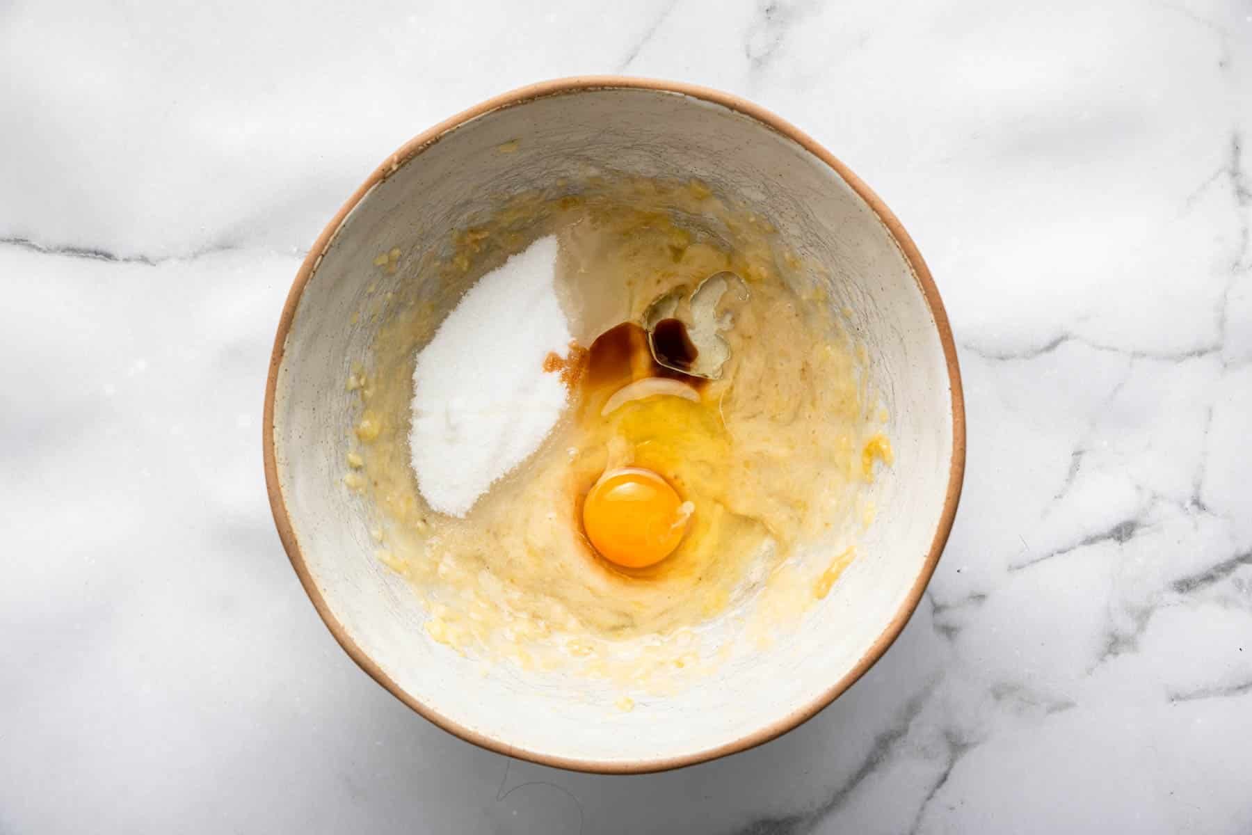 Bowl with sugar, egg, vanilla and mashed fruit in the bottom for baking.