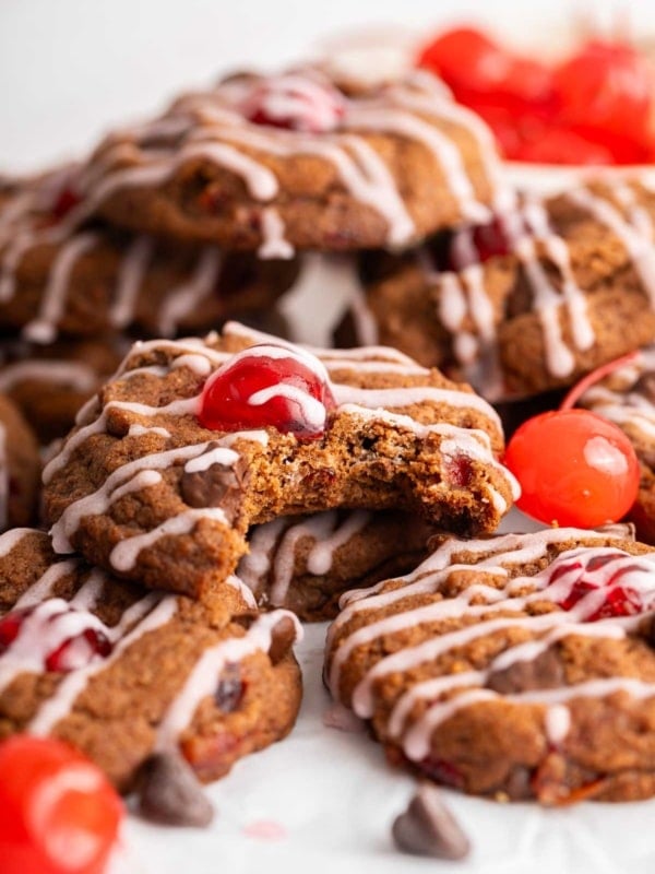 Macro shot of chocolate cookies with cherry on top and pink maraschino drizzle.