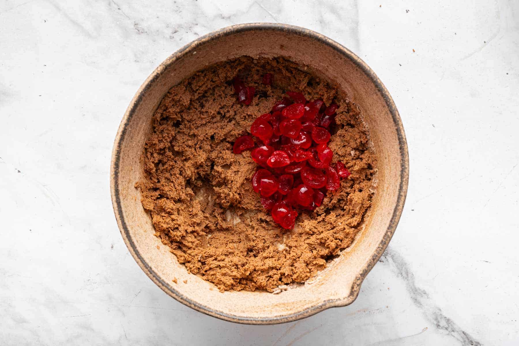 Chopped cherries on top of chocolate cookie batter.