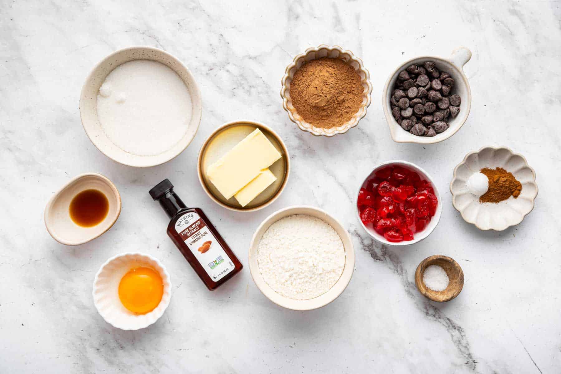 Small bowls of egg yolk, cocoa powder, chocolate chips, and sugar.