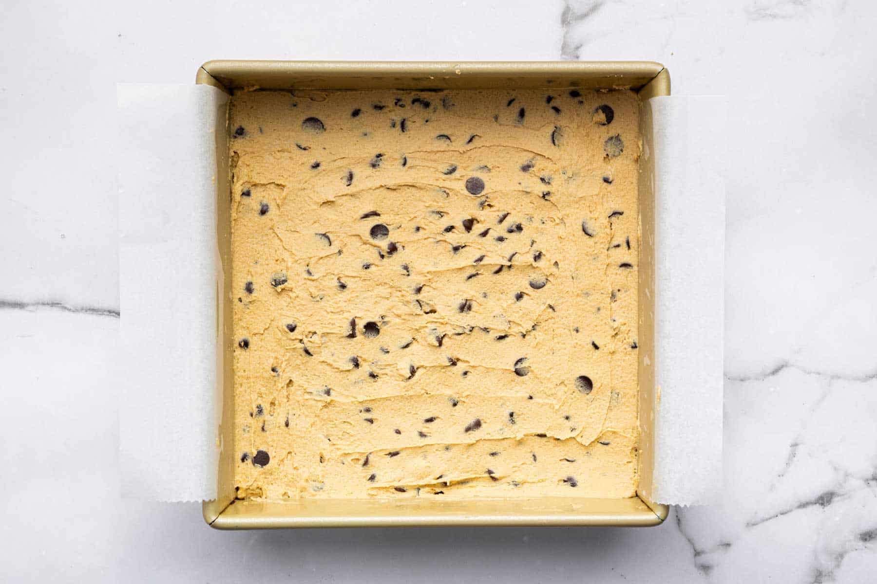 Raw cookie dough in a square pan.