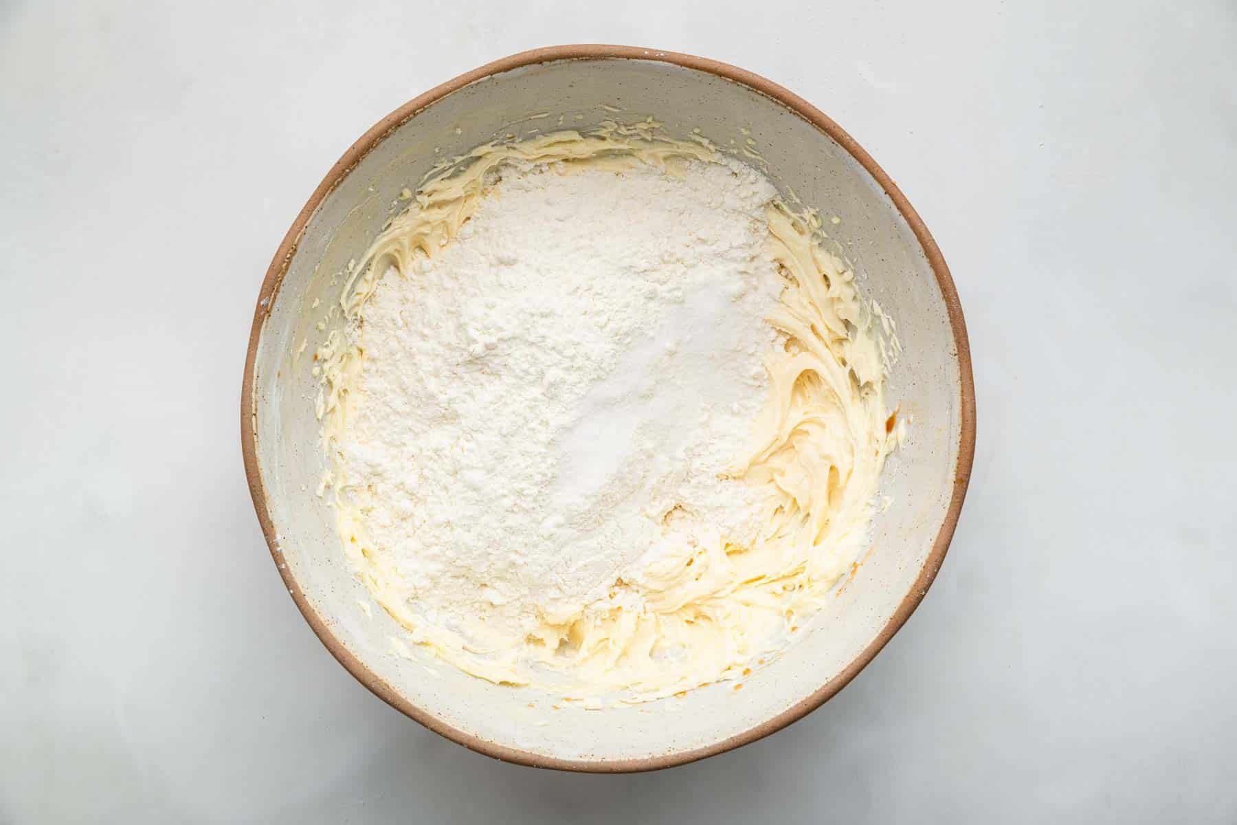 Mixing bowl with creamed butter and powdered sugar on top.