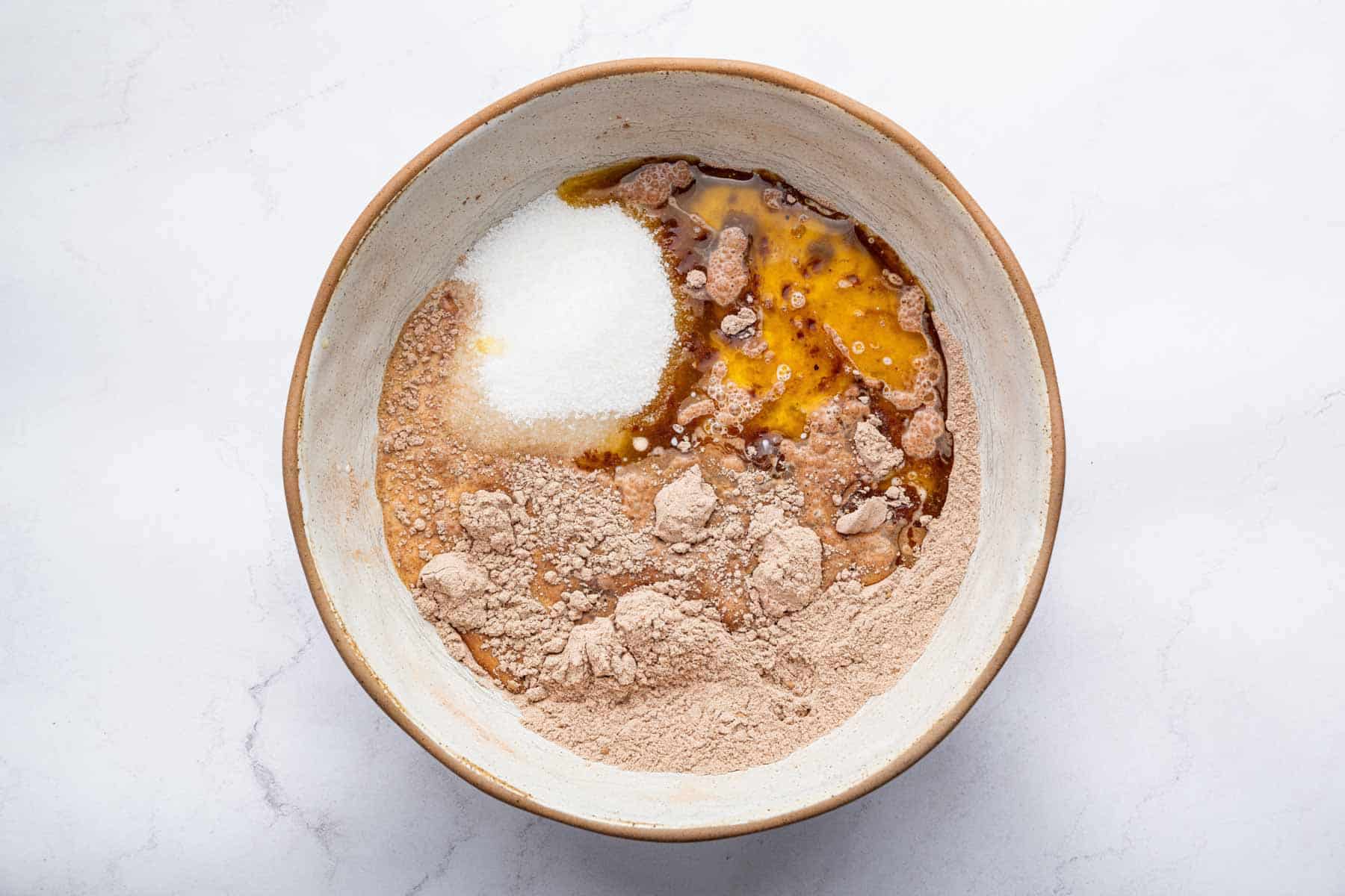 Lumpy batter with melted butter, milk, and powdery ingredients in a bowl.