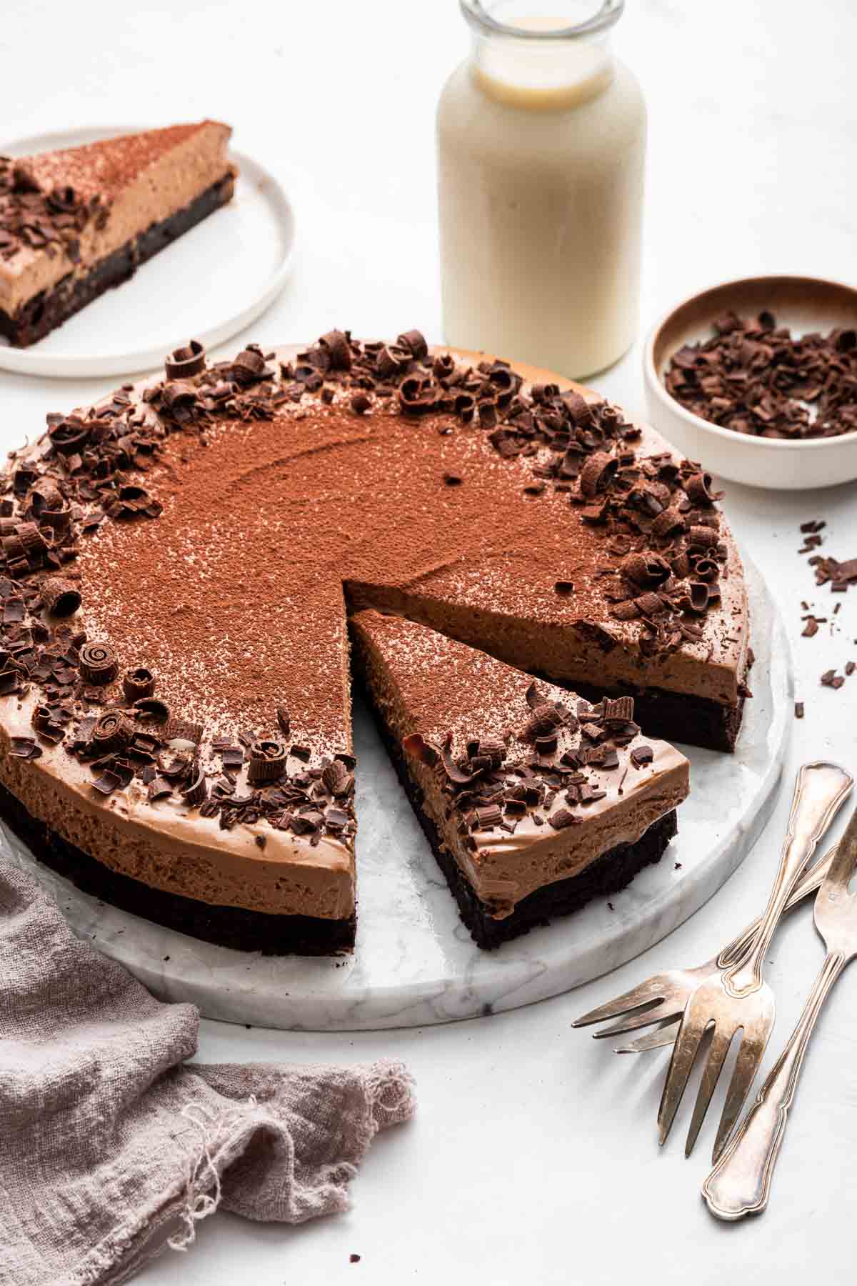 One slice missing from a chocolate mousse cake decorated with shaved chocolate.