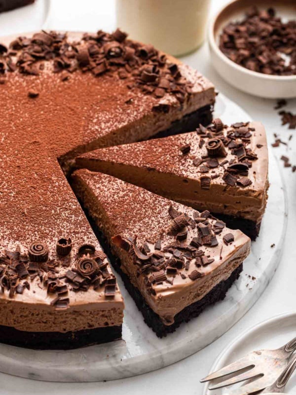 Beautiful sliced chocolate mousse cake on a marble round board.
