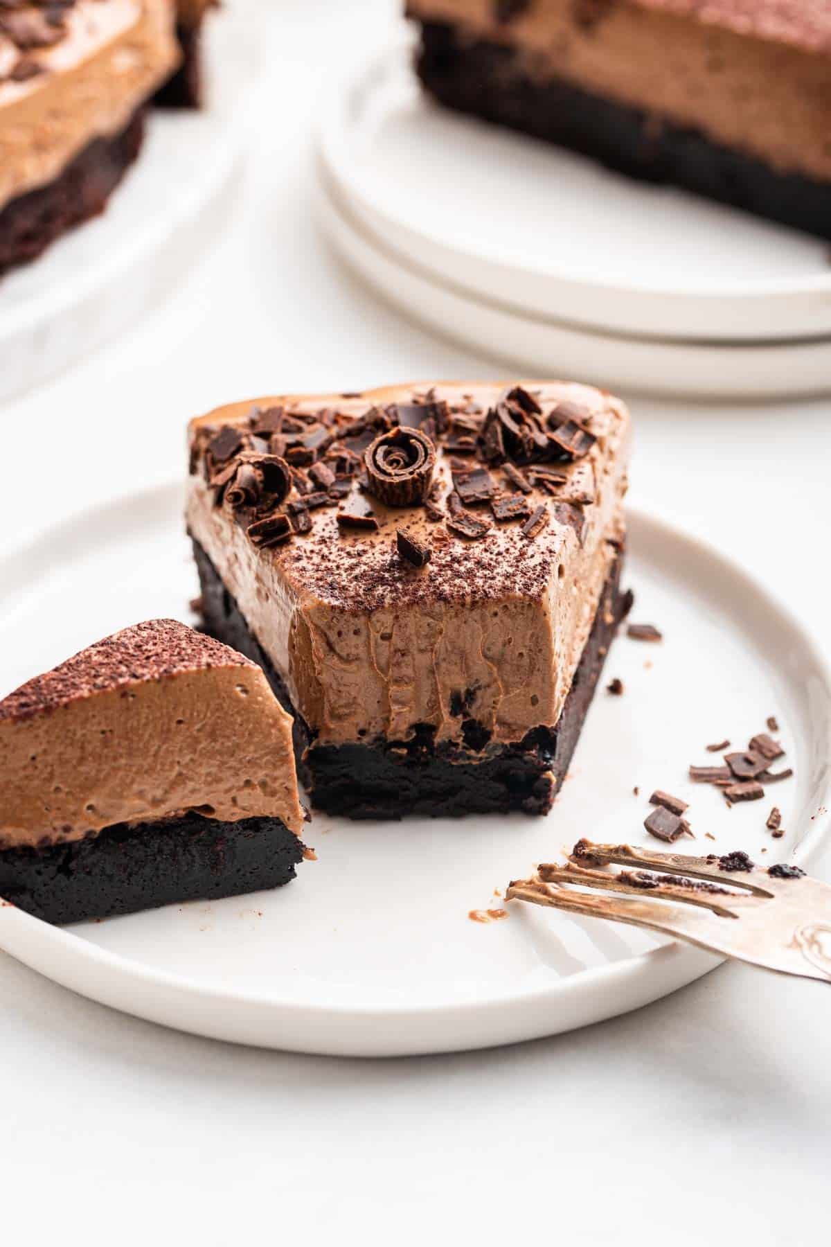 Slice of chocolate mousse cake with one bite missing and shaved chocolate on top.