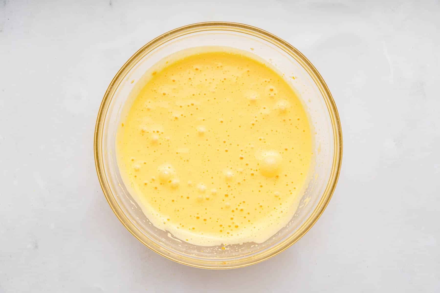 Fluffy yellow batter in clear bowl.
