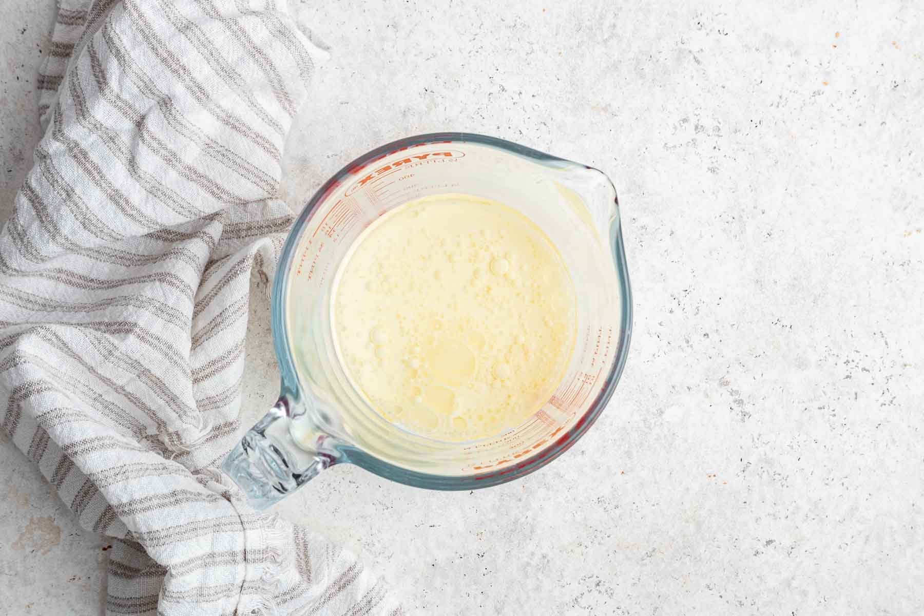 Milk and oil whisked together in glass measuring cup.