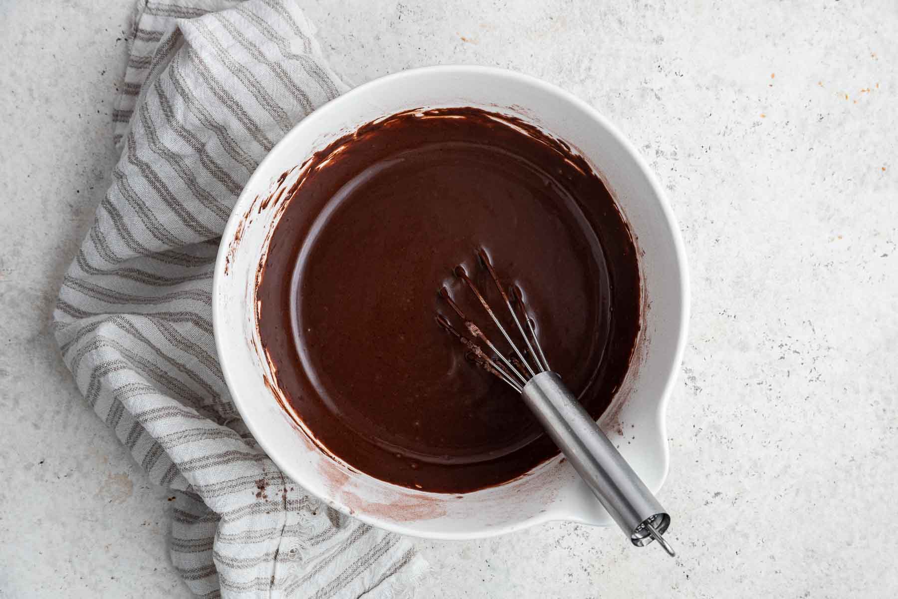 Brown batter in a white bowl with whisk.