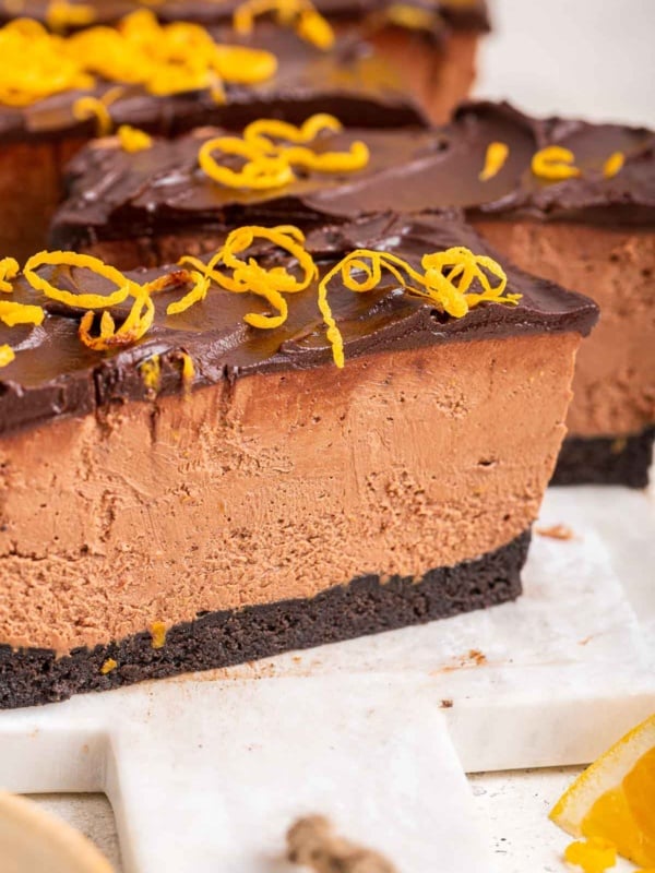 Macro shot of chocolate orange cheesecake slice topped with orange zest curls.