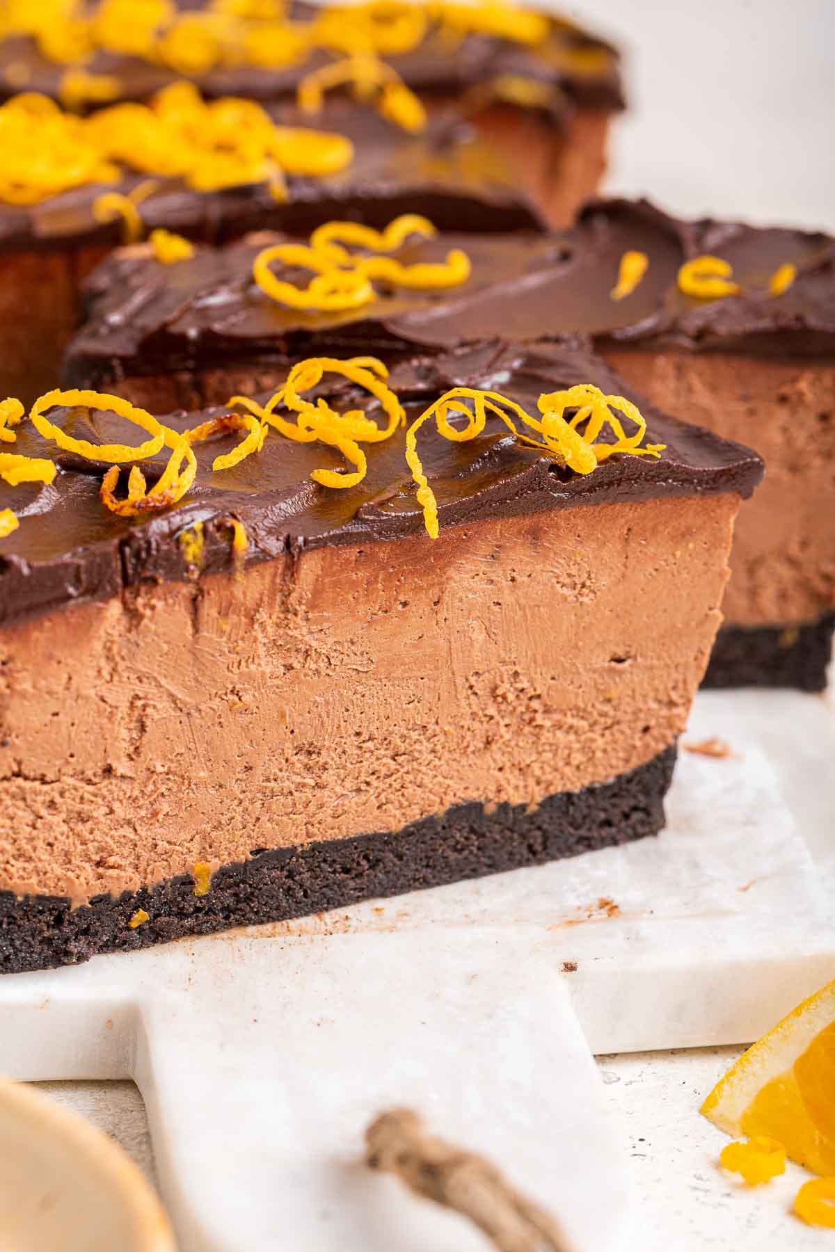 Macro shot of chocolate orange cheesecake slice topped with orange zest curls.