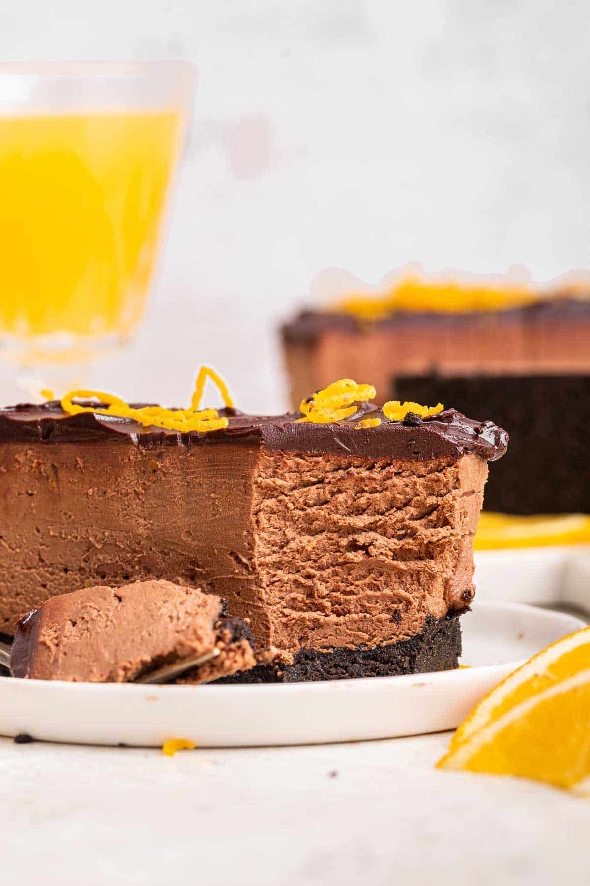 Bite missing from a chocolatecheesecake slice with orange zest on top.