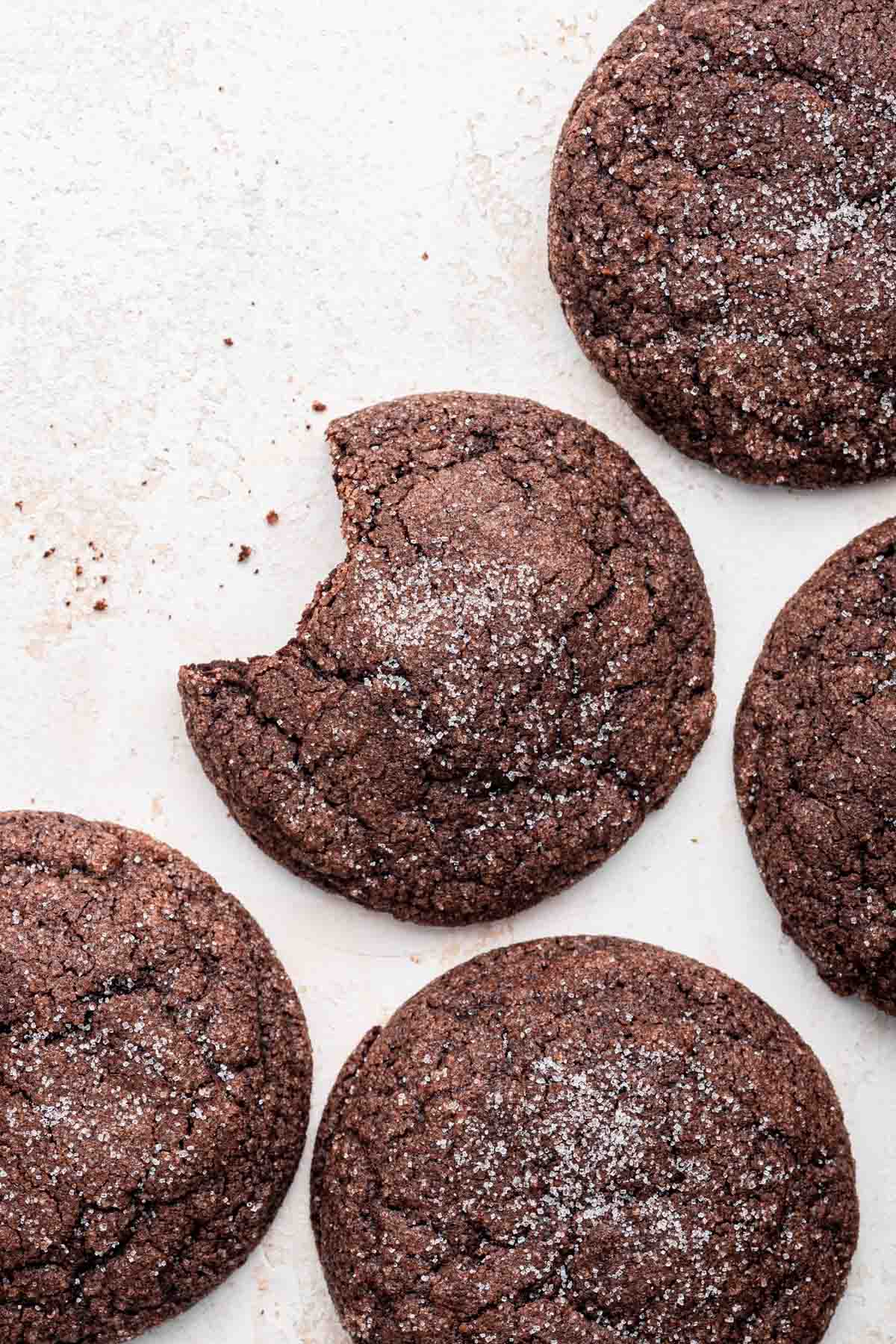 Overhead shot of five chocolate sugar cookies with one bite missing from the center cookie.