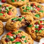 Pile of Christmas monster cookies studded with red and green M&Ms and Christmas sprinkles.