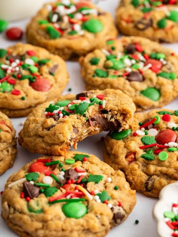 Pile of Christmas monster cookies studded with red and green M&Ms and Christmas sprinkles.