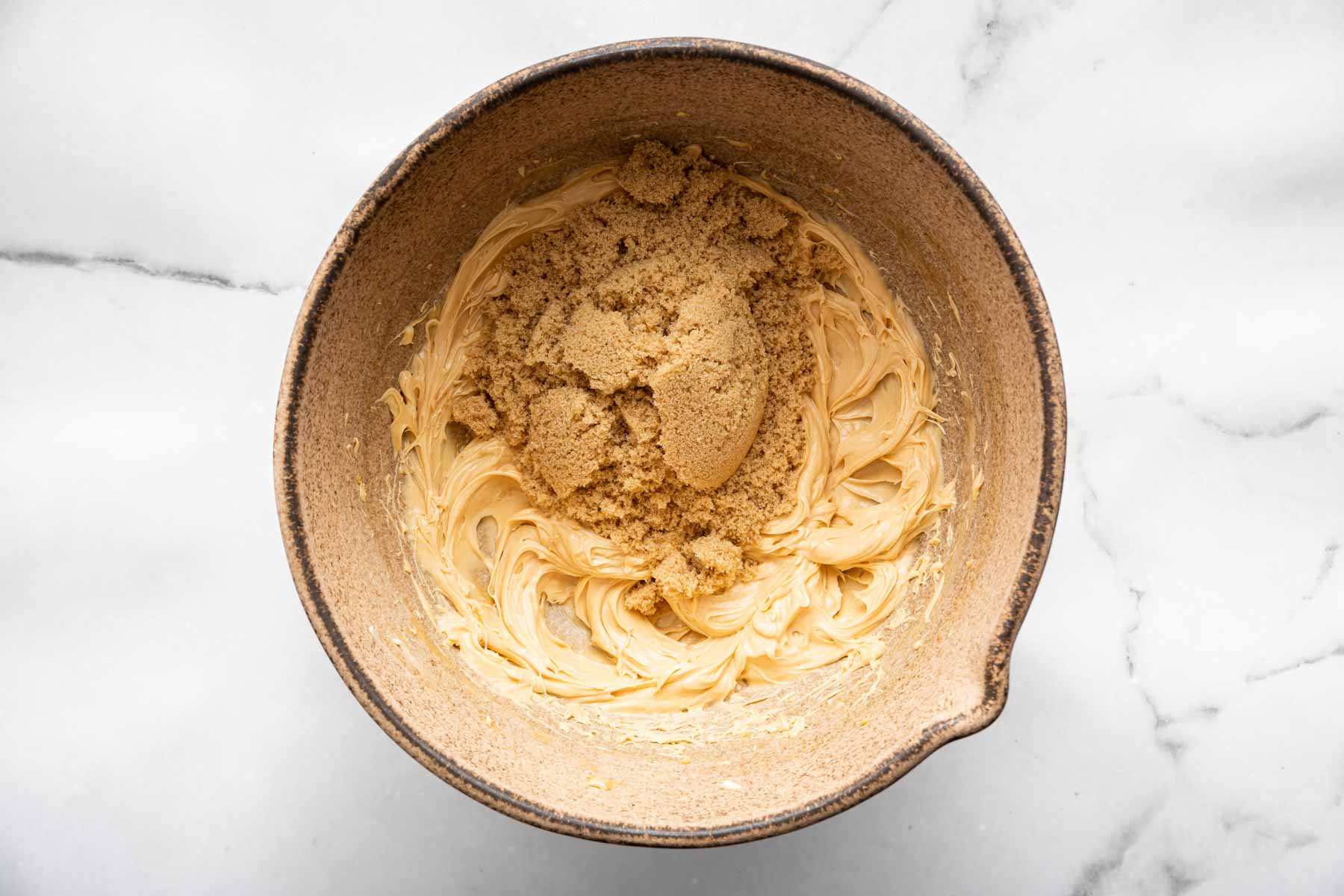 Whipped yellow batter with a scoop of brown sugar on top.
