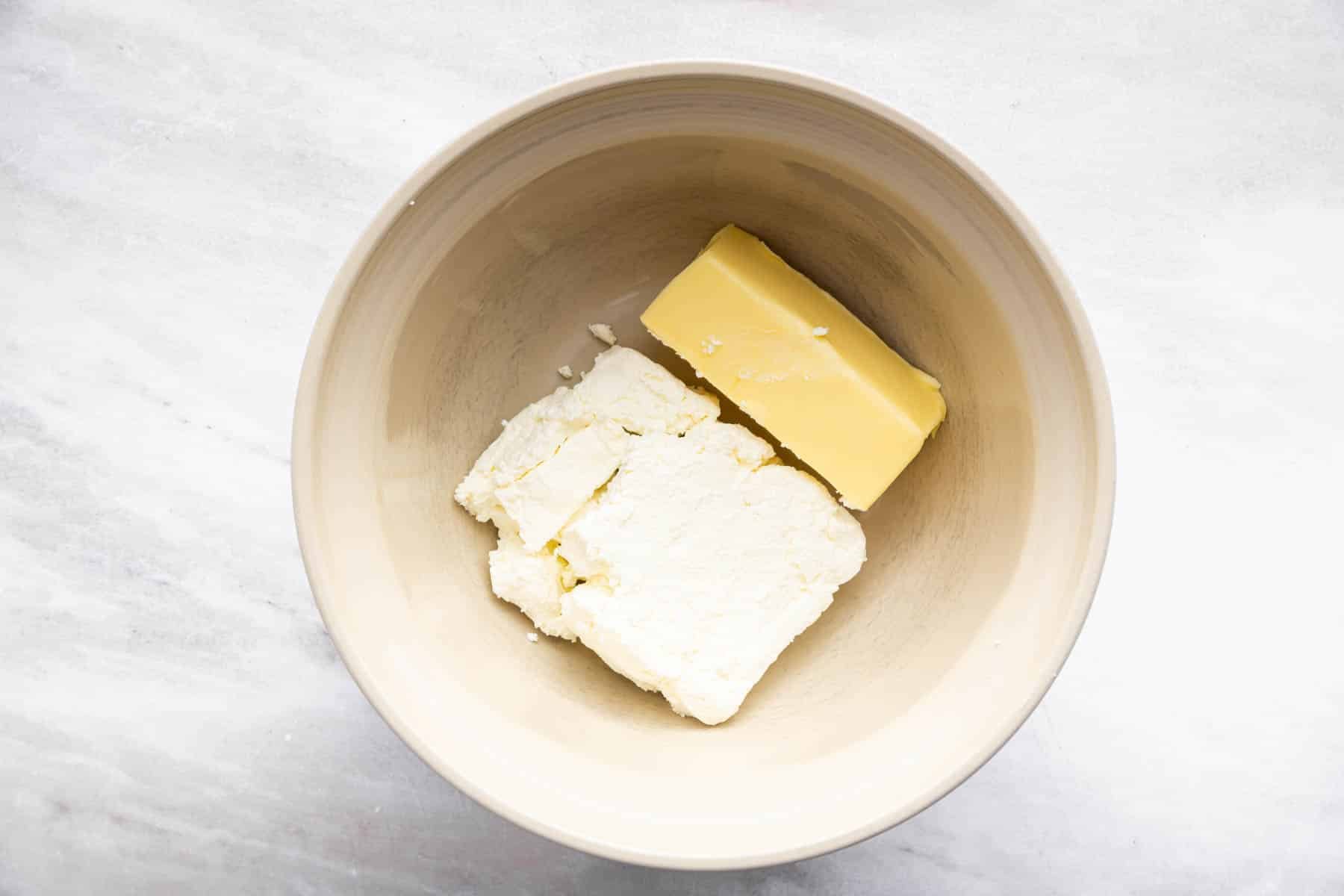 Bowl with brick of cream cheese and stick of butter.