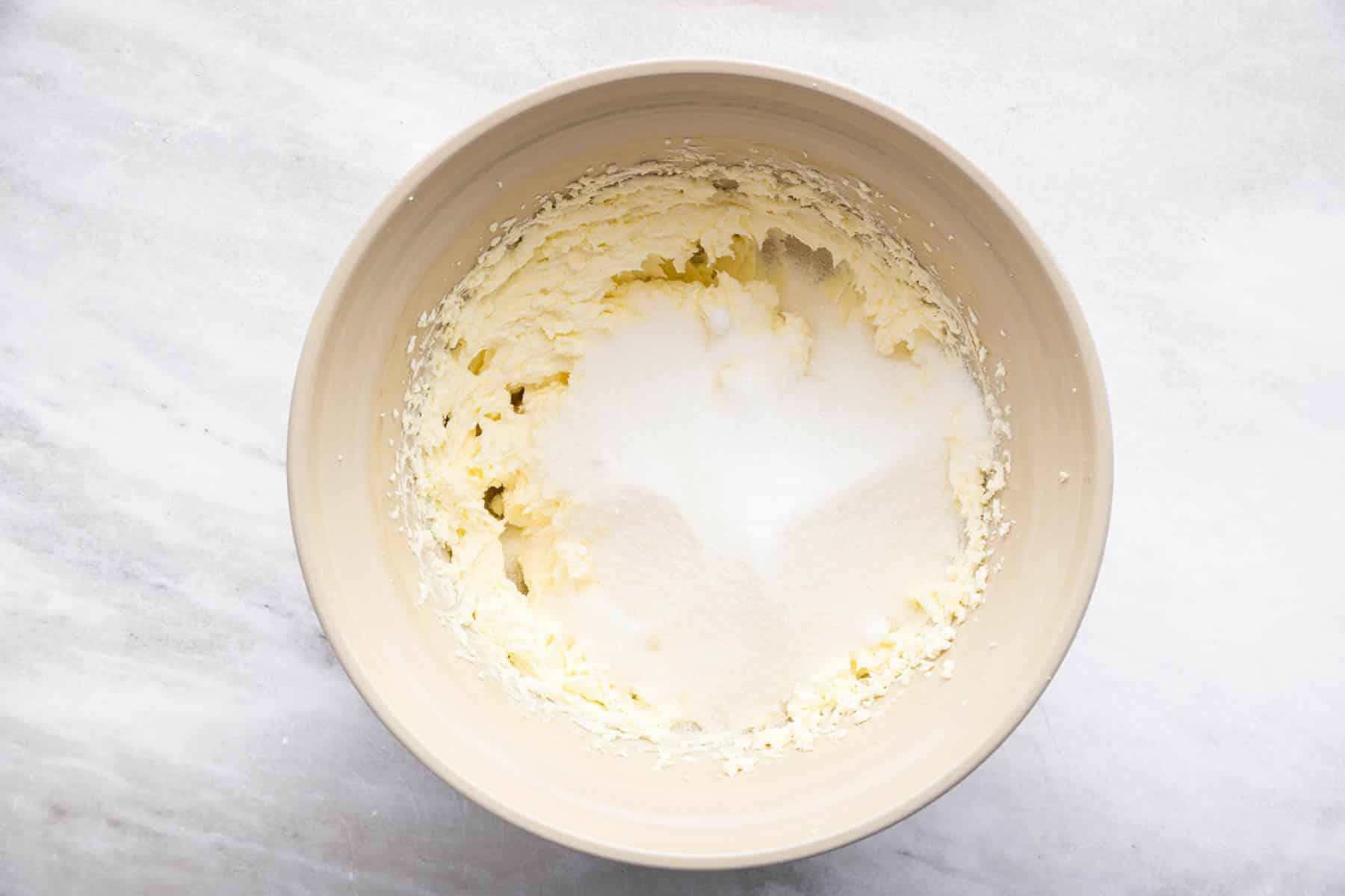 Bowl with white flour and baking powder splashed on fluffy batter.