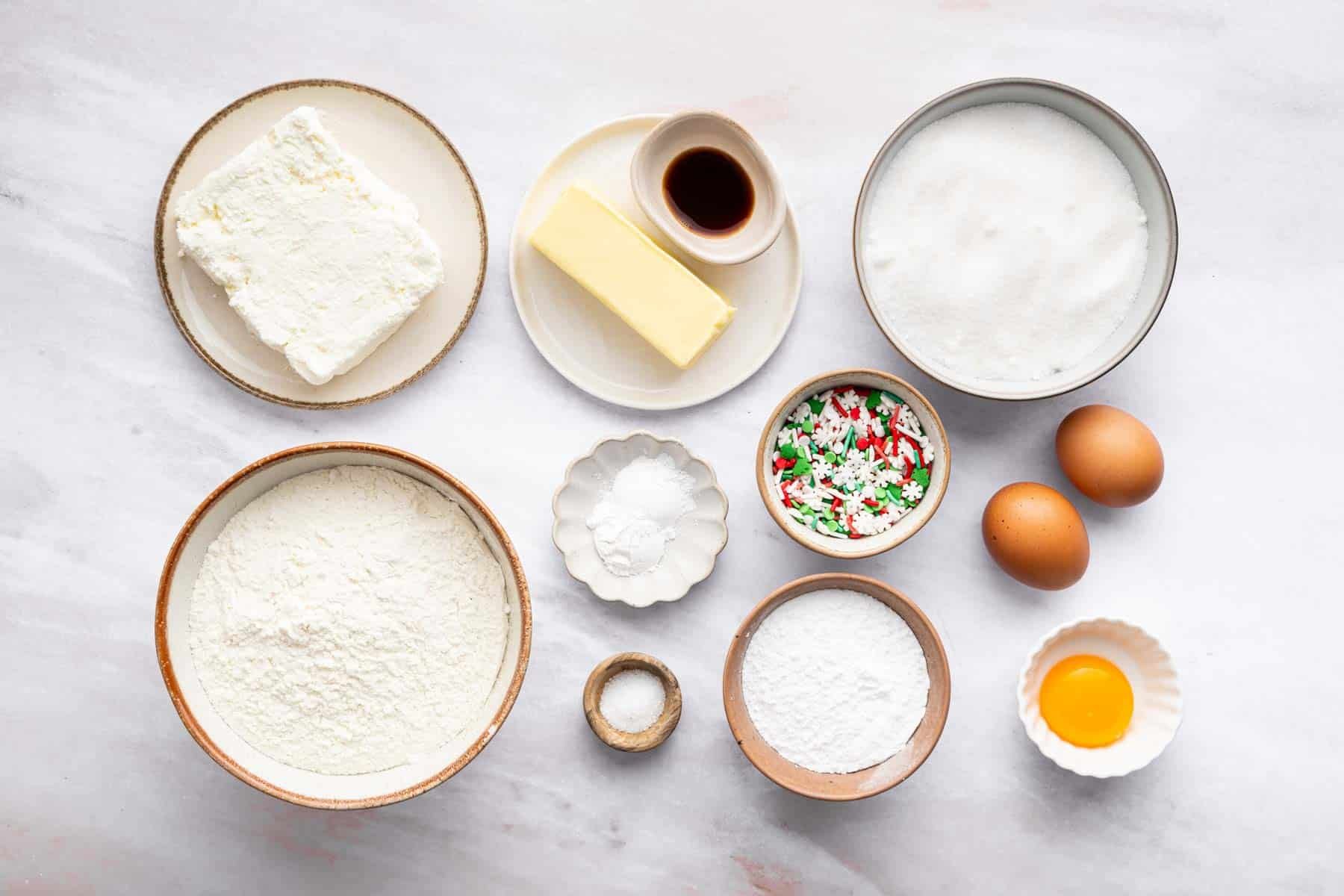 Small bowls with baking ingredients and festive sprinkles.