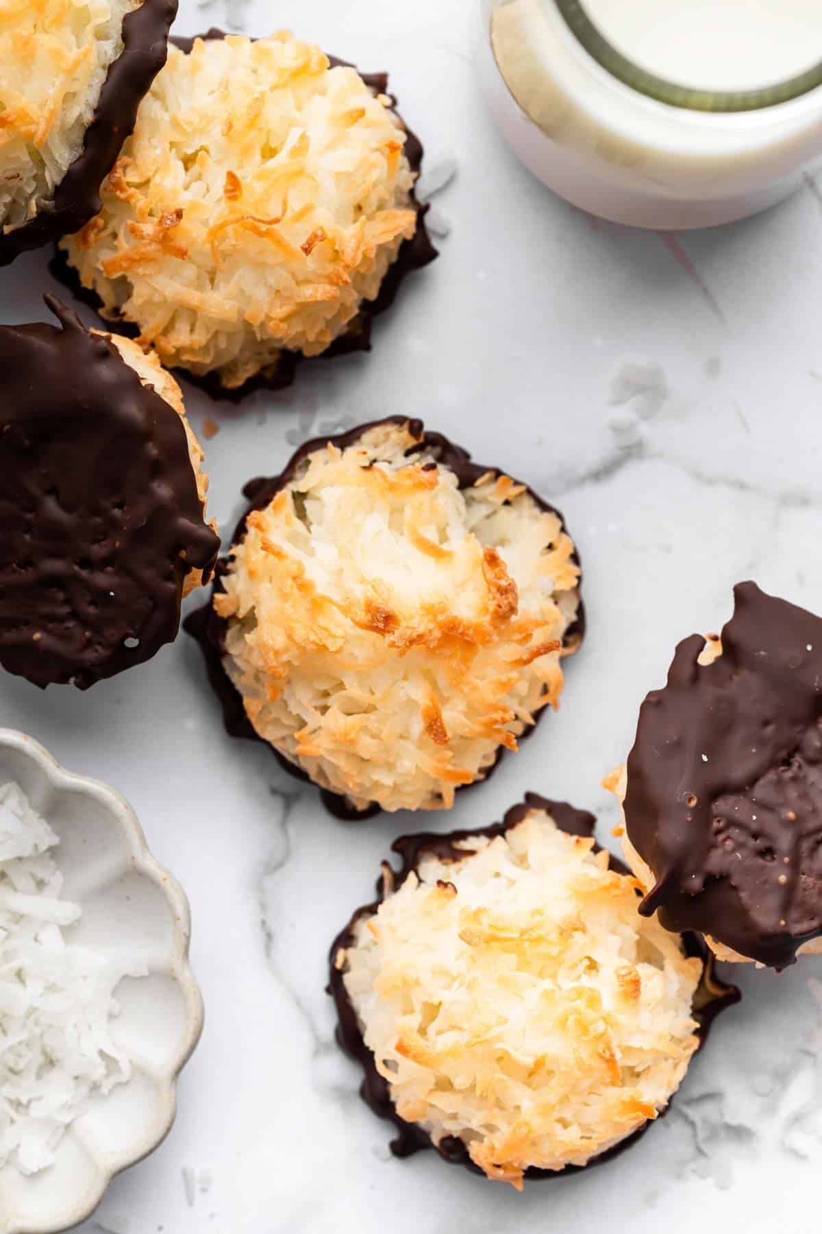 Coconut macaaroons dipped in chocolate on the bottom on a marble counter.